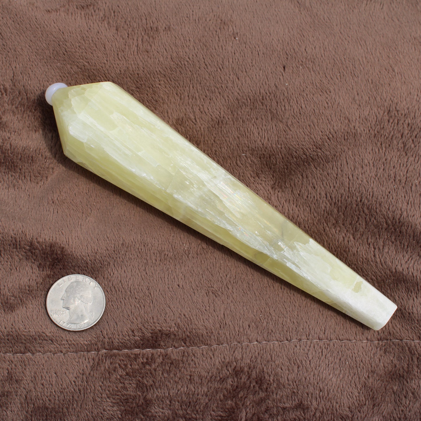 Lemon Quartz Wand crystal by Different Branches LLC displayed next to a quarter for size reference