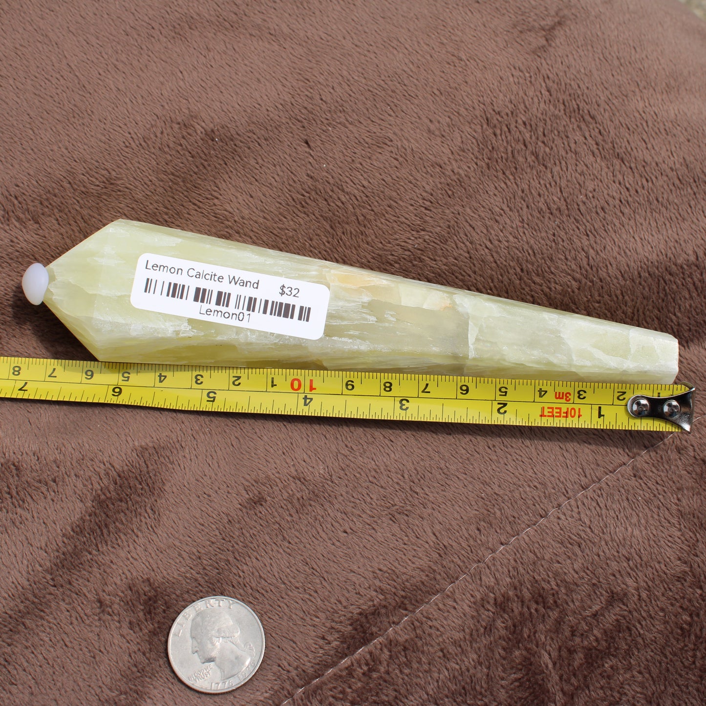Lemon Quartz Wand crystal from Different Branches LLC placed next to a tape measure and a quarter for size reference