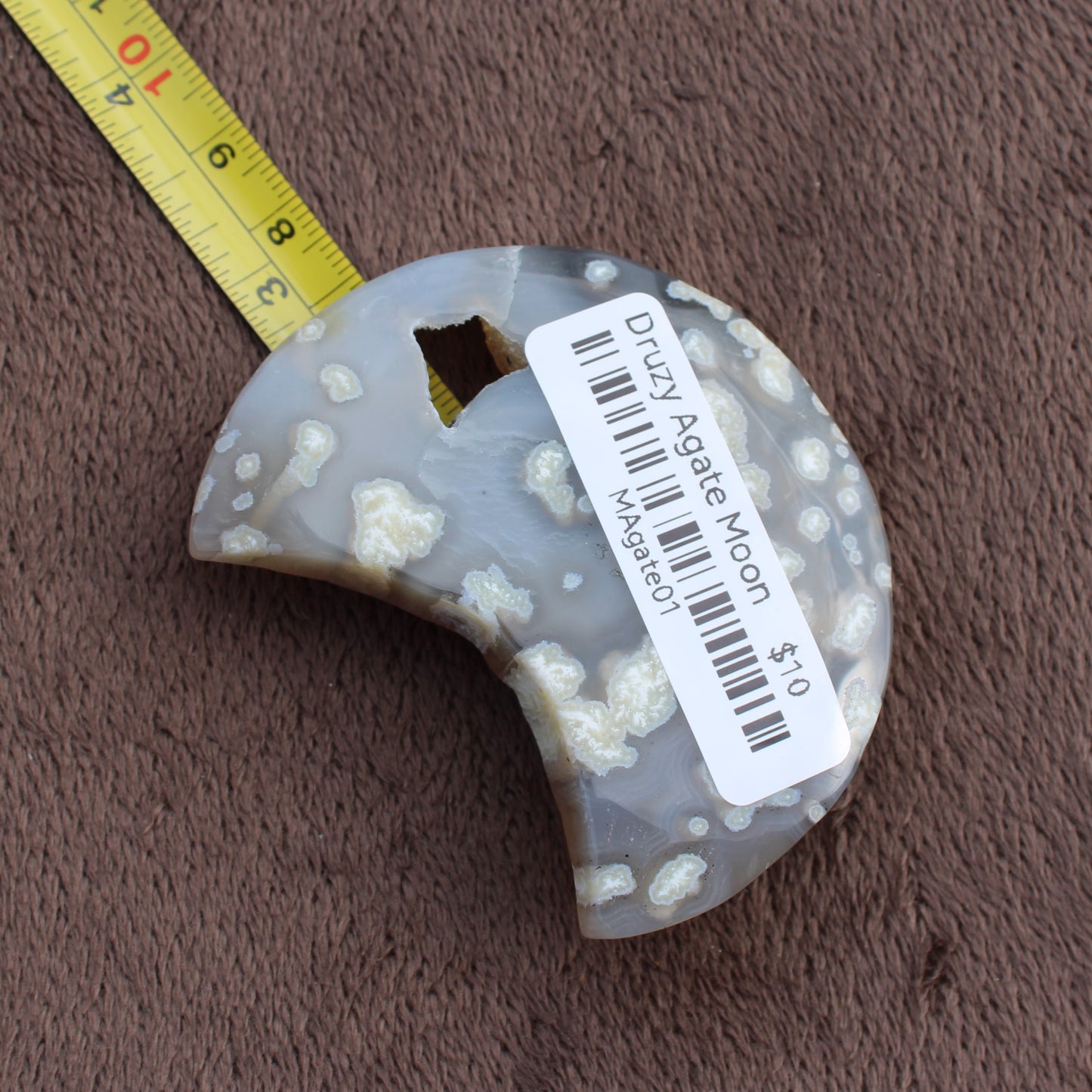 Little Agate Moon crescent-shaped crystal from Different Branches LLC with natural patterns and measuring tape