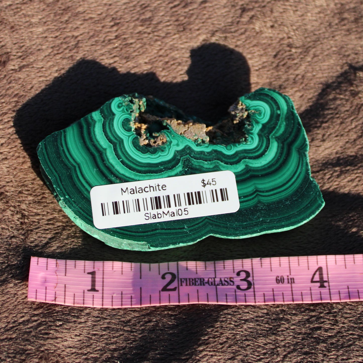 Natural Malachite slab with rich green bands displayed on a textured surface for home decor