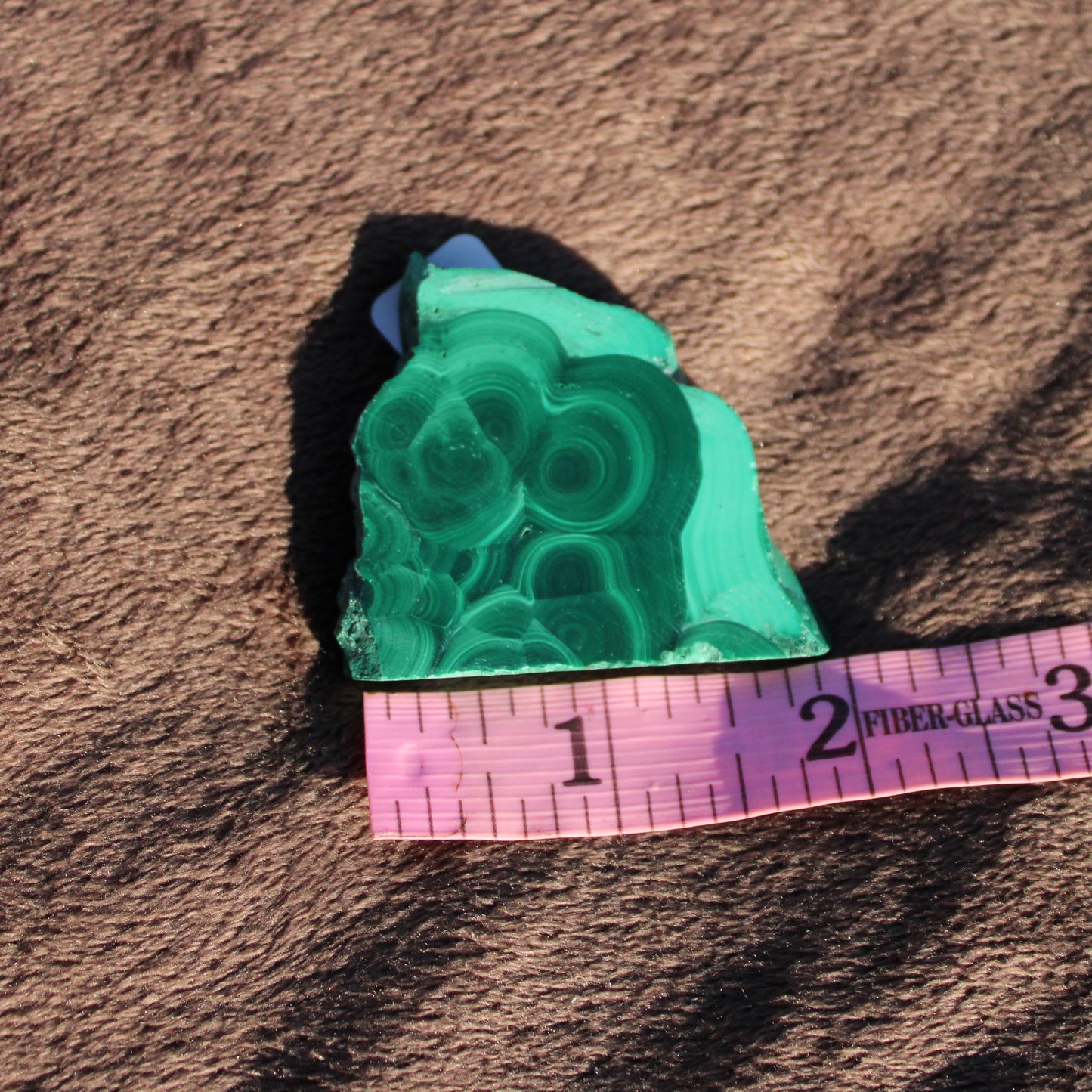 Natural Malachite slab showcasing vibrant green patterns with a measuring tape for size reference