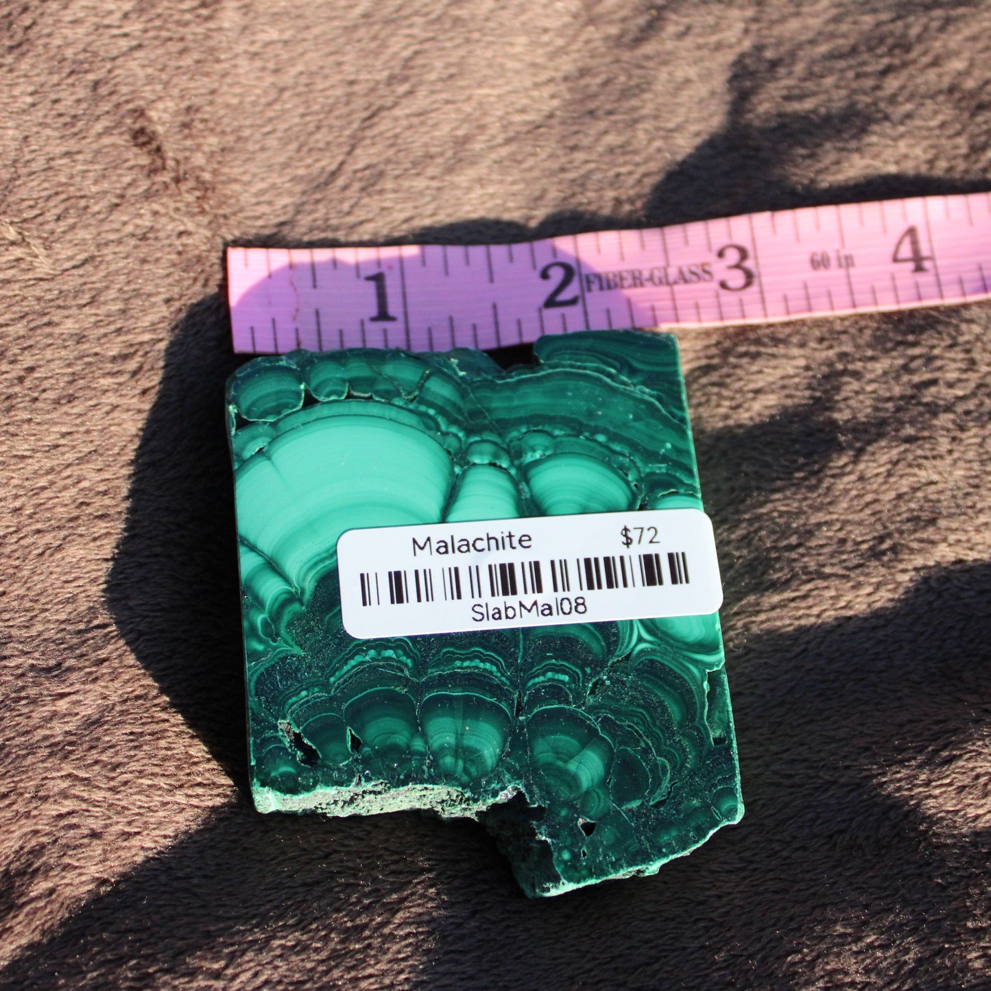 Natural Malachite slab showcasing vibrant green patterns with price tag from Different Branches LLC
