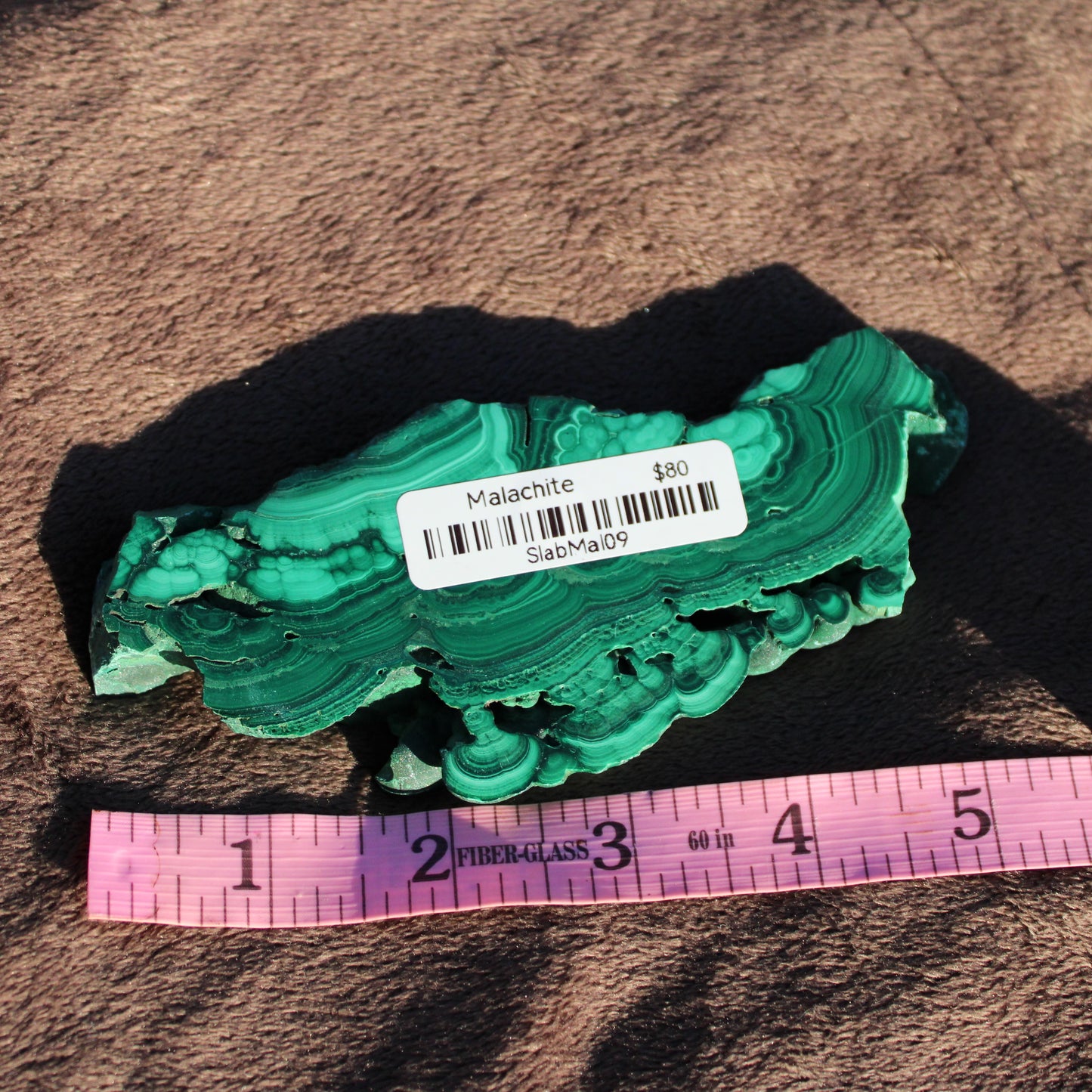 Natural Malachite slab showcasing vibrant green banding with a ruler for size reference