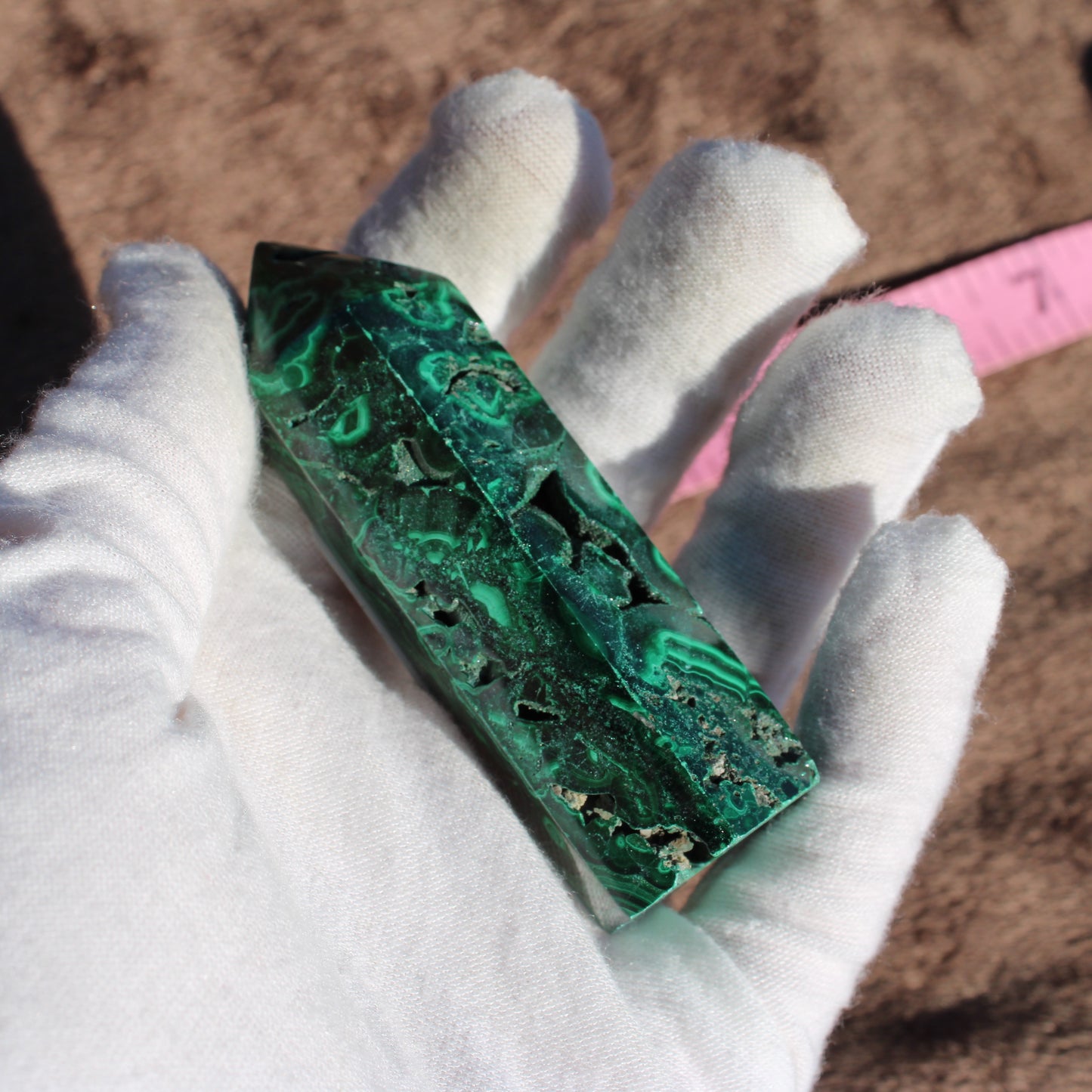 Malachite tower collection displayed in hand, showcasing rich green patterns and polished finish