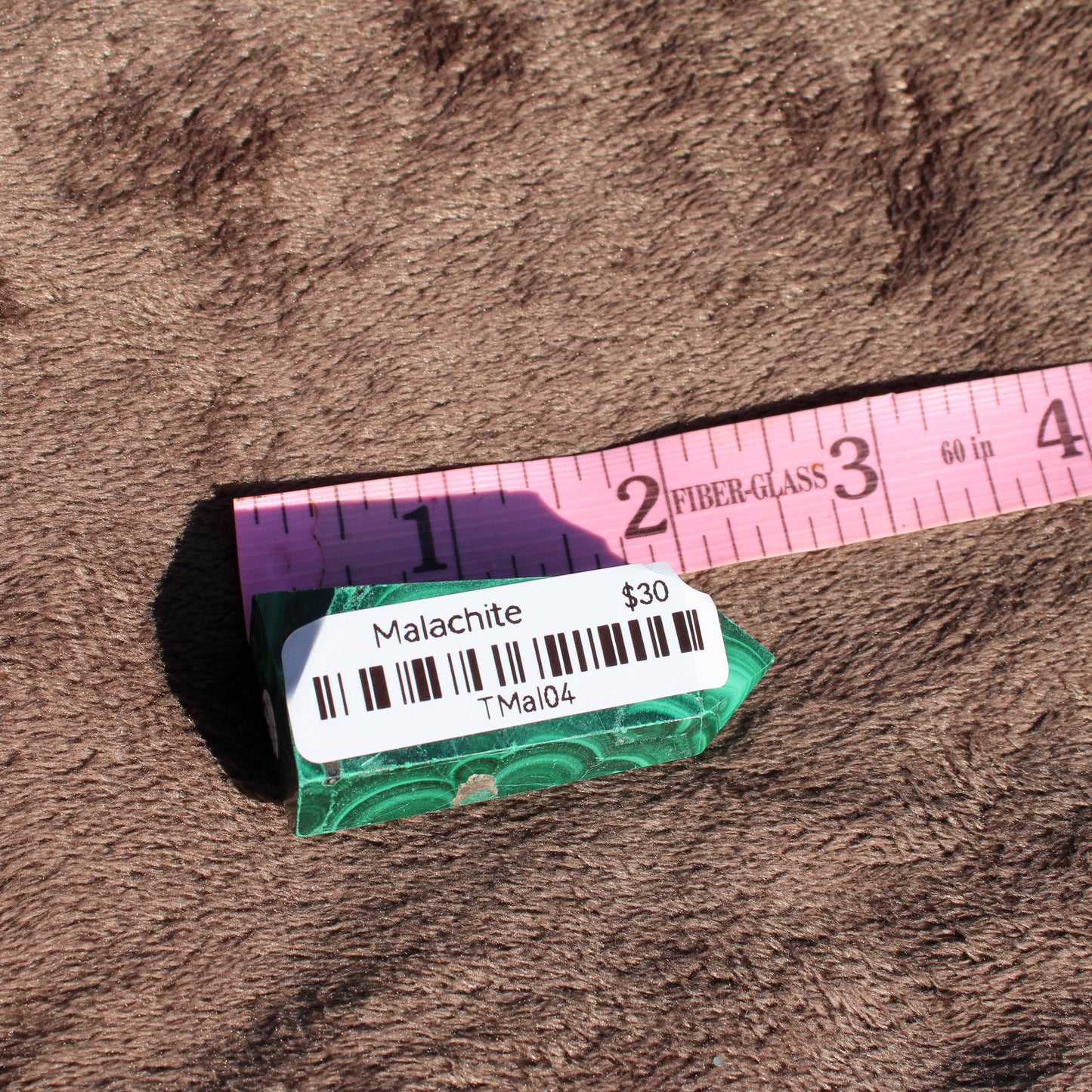 Malachite tower collection displayed on a soft surface with a ruler for size reference