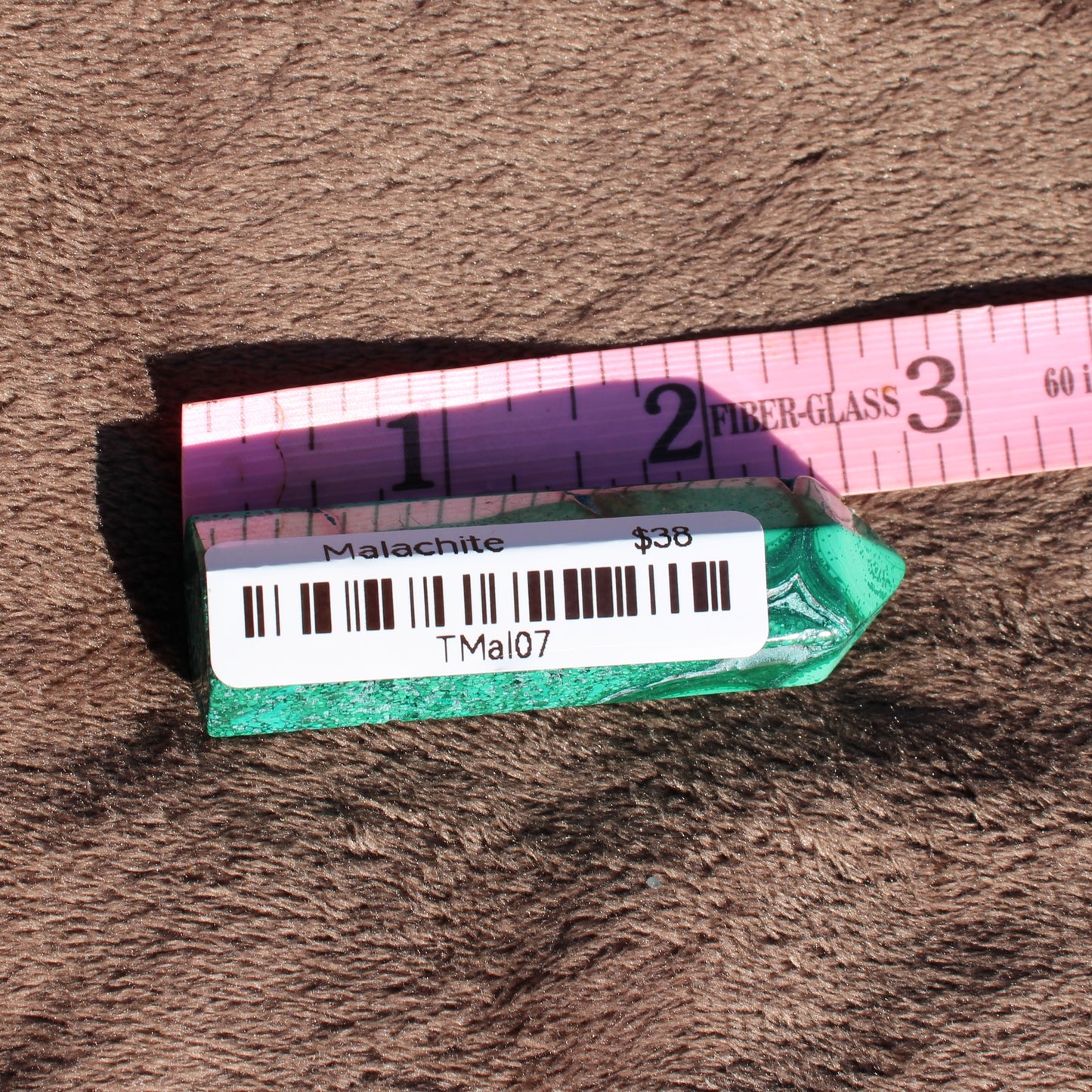 Malachite tower collection displayed on a soft surface with a measuring tape for scale