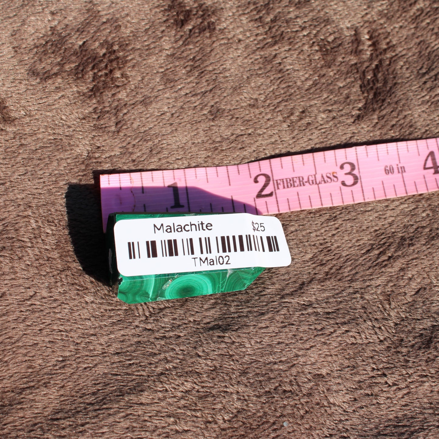 Malachite tower collection with vibrant green patterns and measurement tape for size reference
