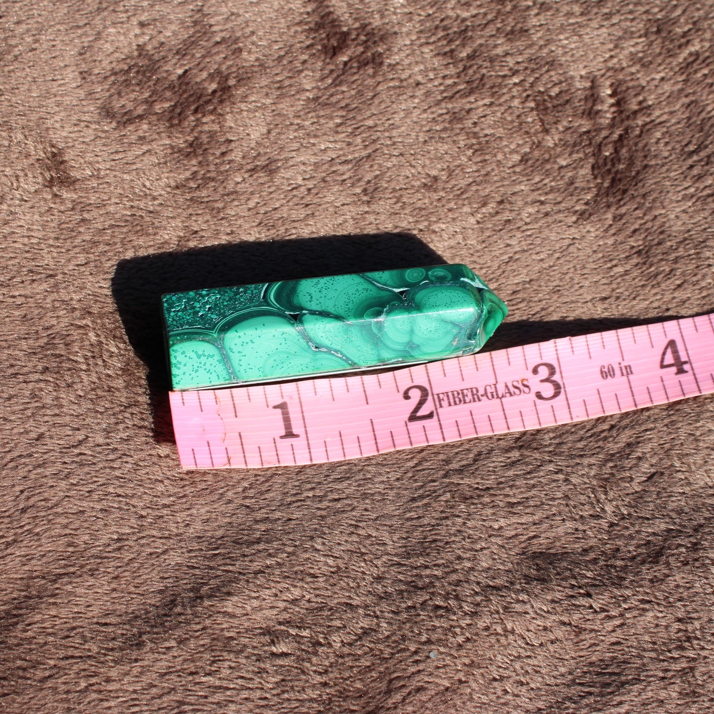 Malachite tower collection crystal with unique patterns and vibrant green hues displayed on a soft background