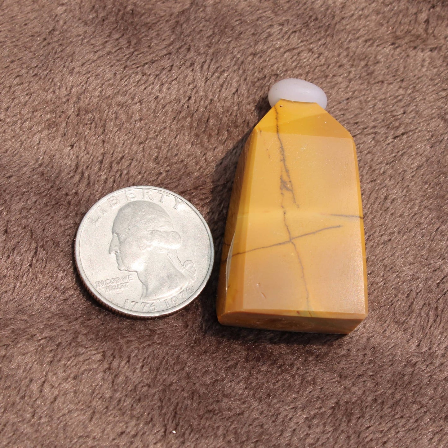 Mini Mookalite towers in yellow with natural patterns next to a quarter for size reference