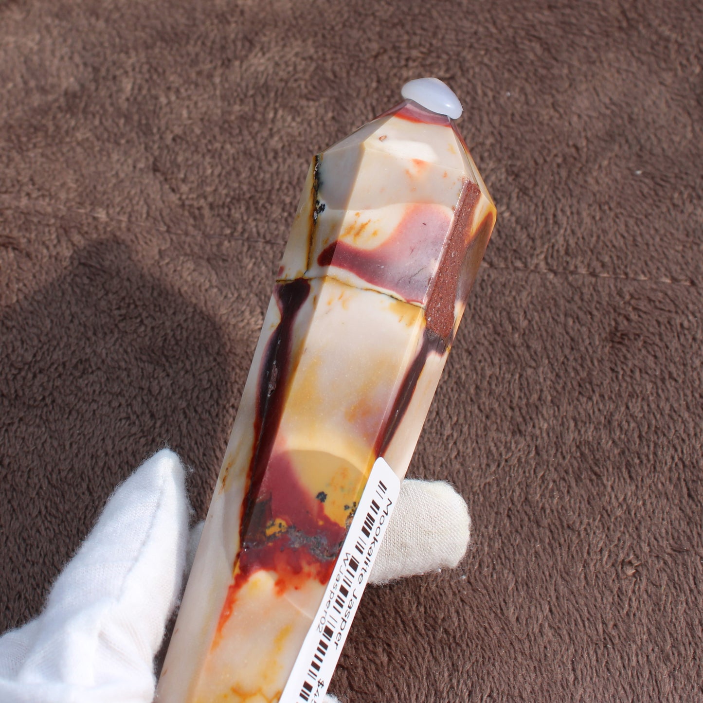 Hand holding polished Mookaite Jasper Wand crystal with natural red and yellow patterns