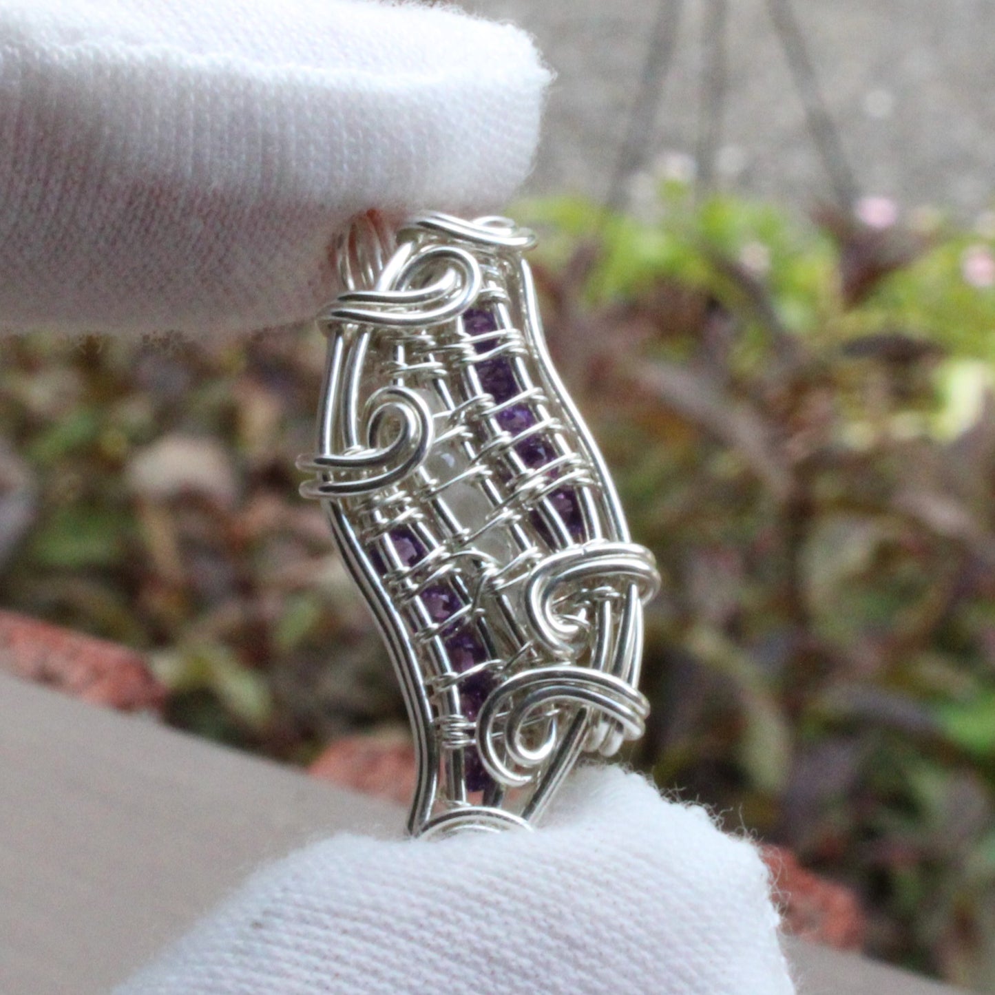 Moonstone, Amethyst, Sterling silver Pendant with intricate wire design held gently in hand