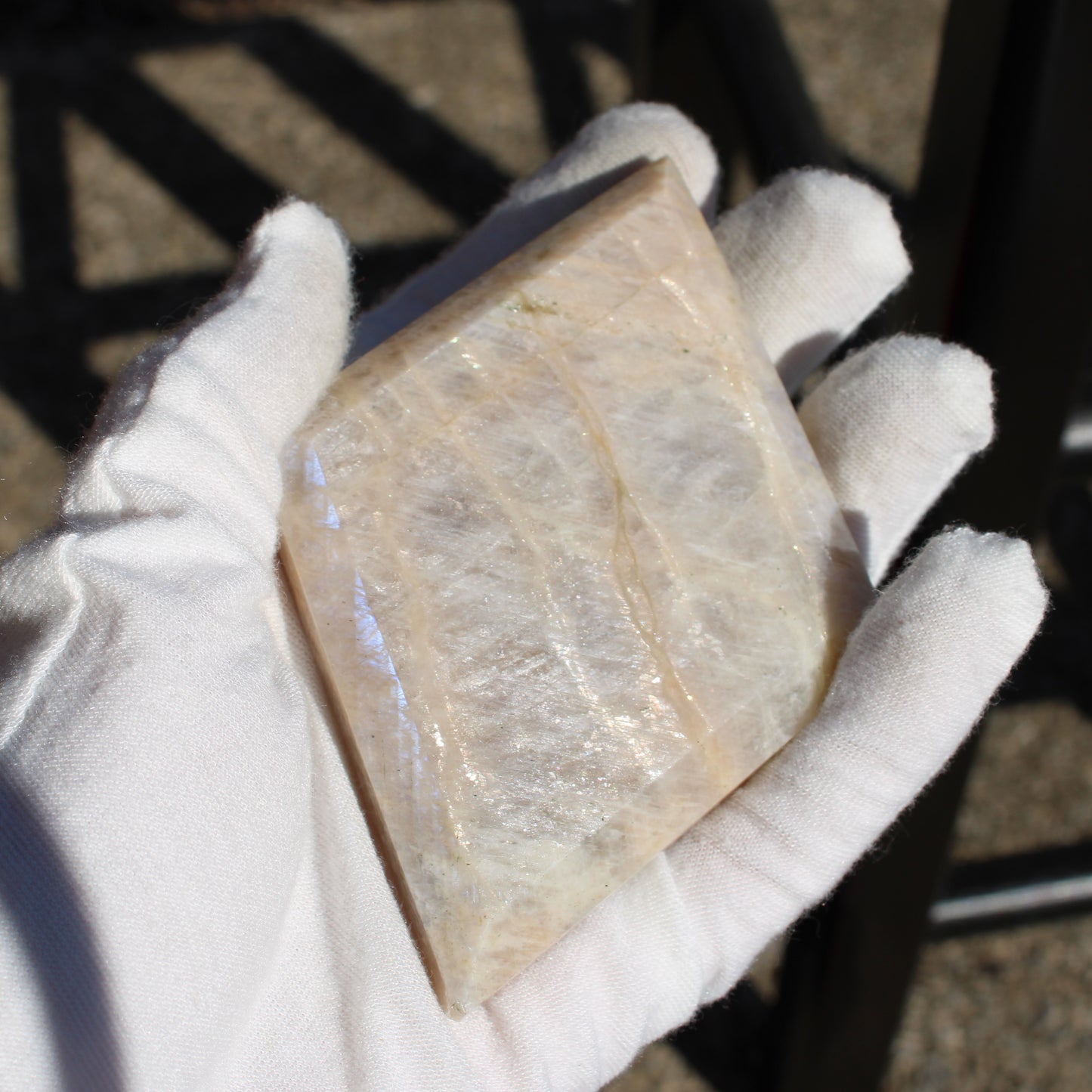 A large piece of moonstone diamond held in a gloved hand, showcasing its translucent texture and natural beauty