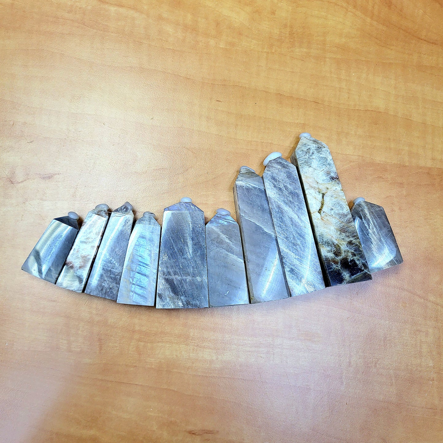 Set of polished moonstone towers arranged in a curving line on a wooden surface