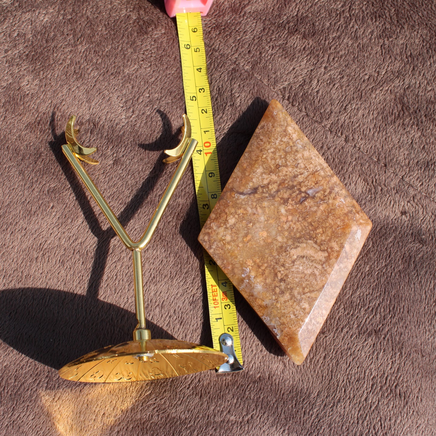 Moss Agate Diamond crystal with gold metal stand and measuring tape on brown fabric