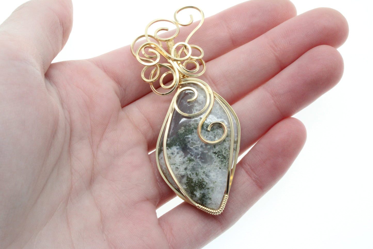Moss agate pendant 14k gold-filled featuring intricate wire design held in a hand