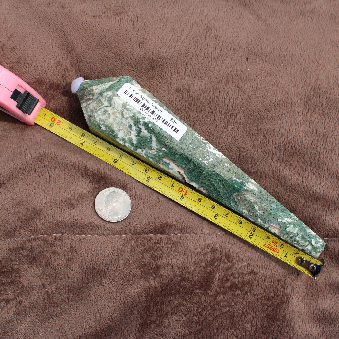 Green and white Moss Agate Wand from Different Branches LLC next to a tape measure and coin for size reference