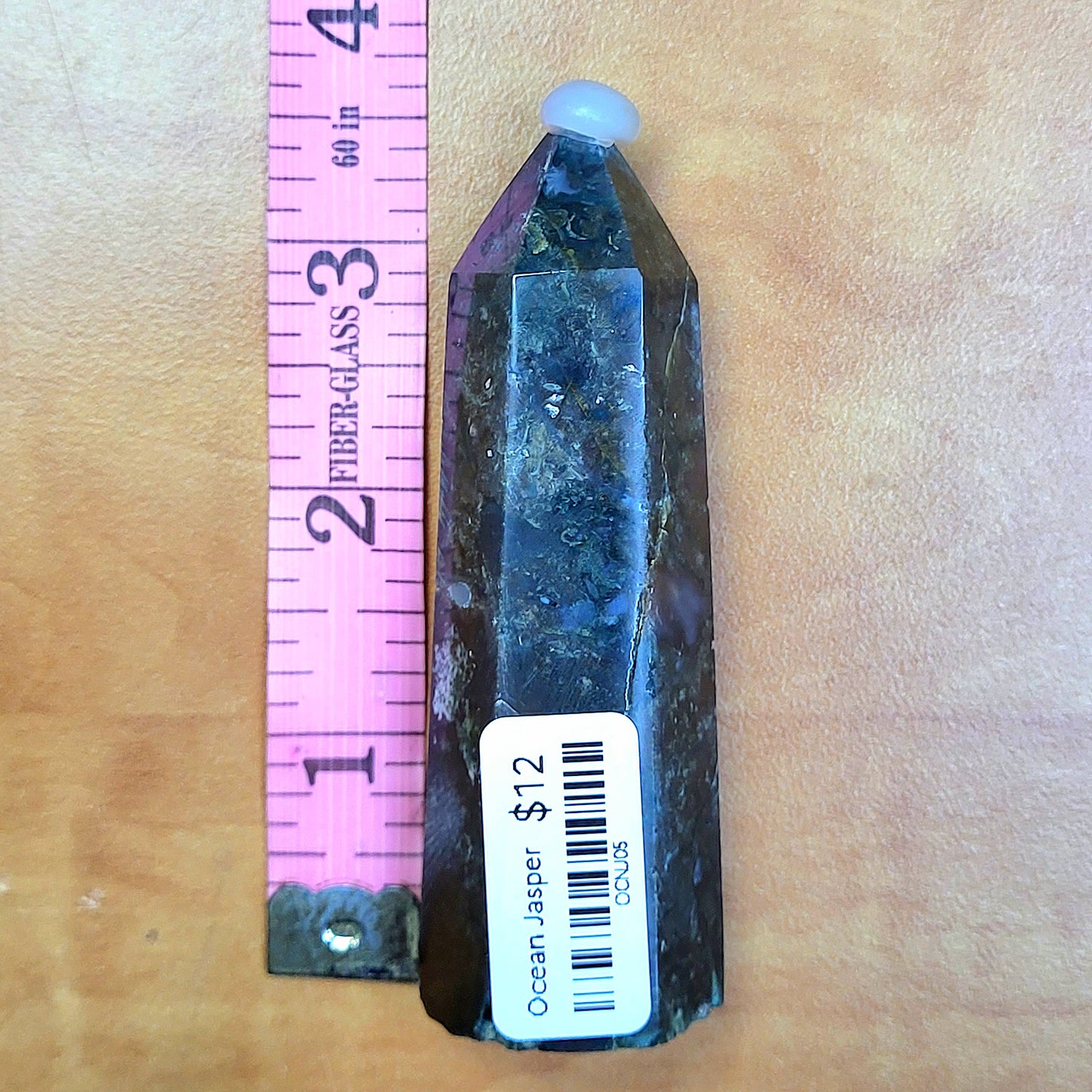 Ocean jasper tower in unique shape with natural stone patterns and a height measurement on a ruler
