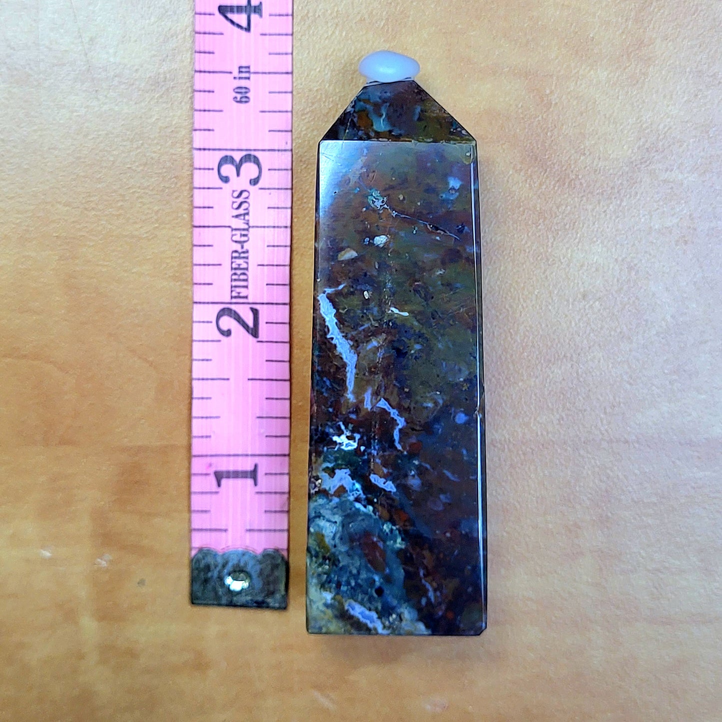 Ocean jasper tower with unique patterns, displayed next to a pink ruler for size comparison