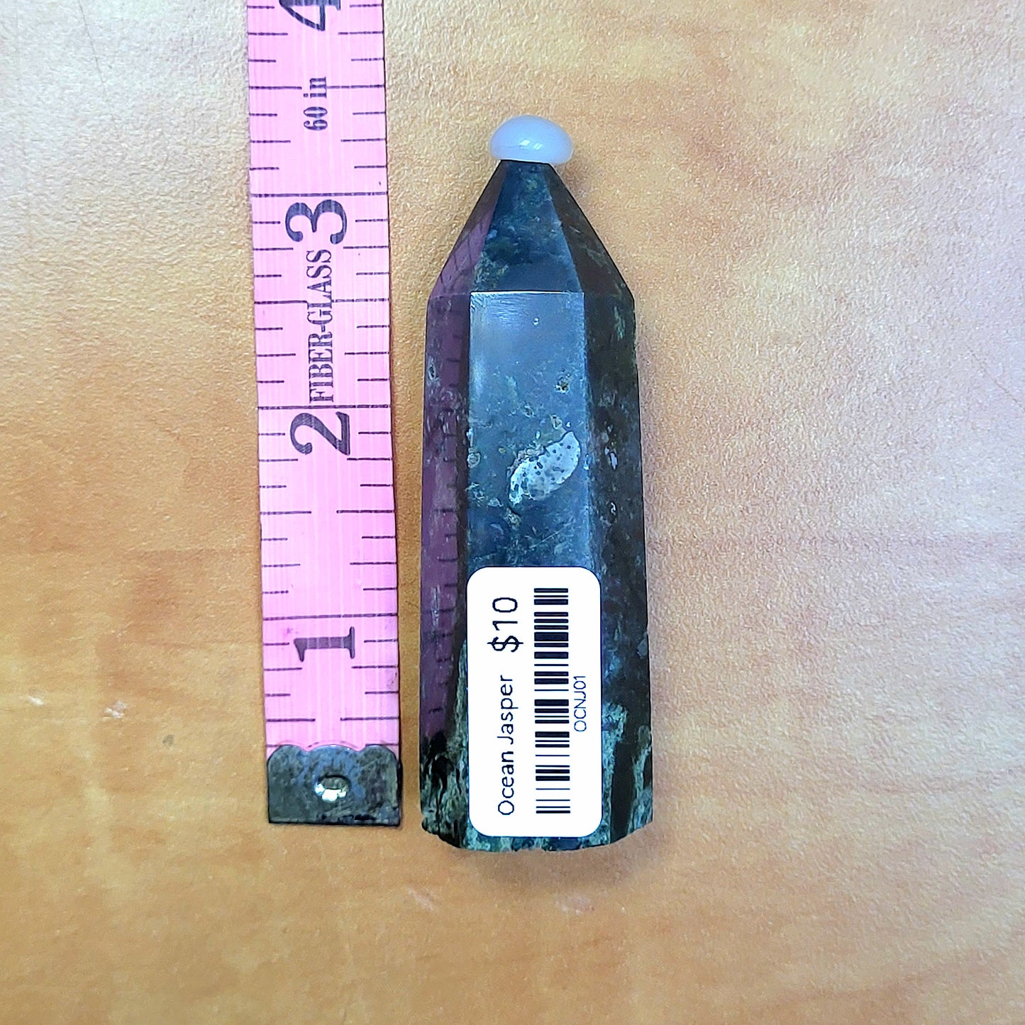 Ocean jasper tower in unique colors, standing next to a ruler for size reference