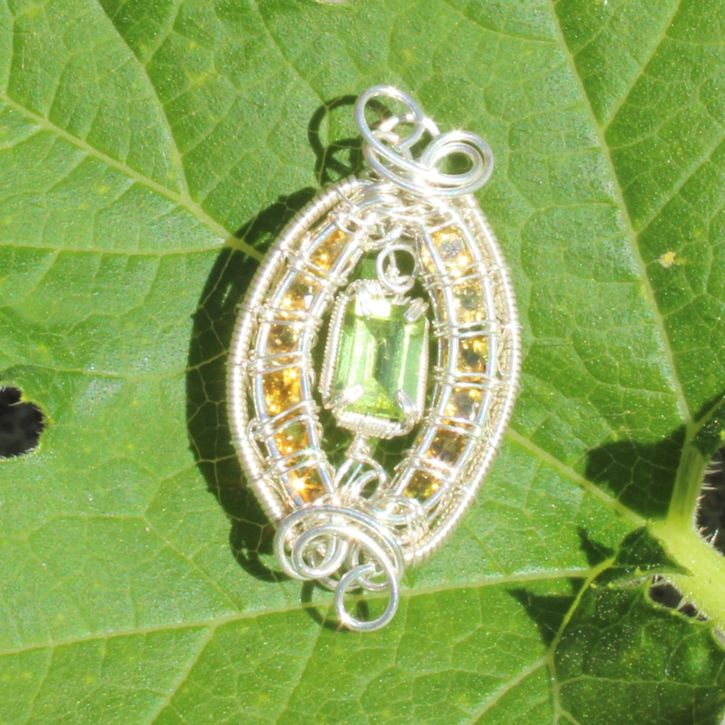 Elegant Peridot Sterling Silver yellow tourmaline pendant with intricate wire design on leaf background