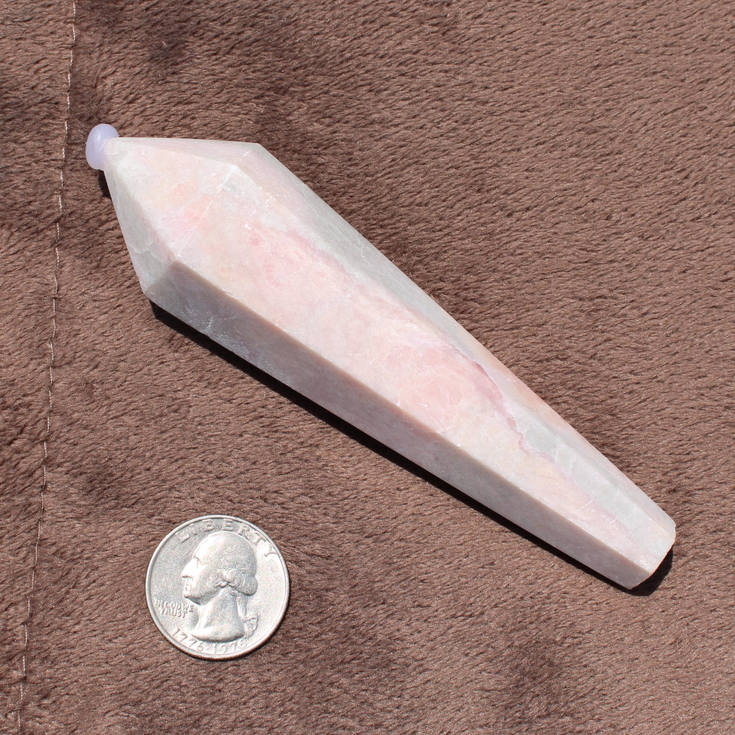 Pink Opal Wand crystal with polished facets shown next to a quarter for size reference