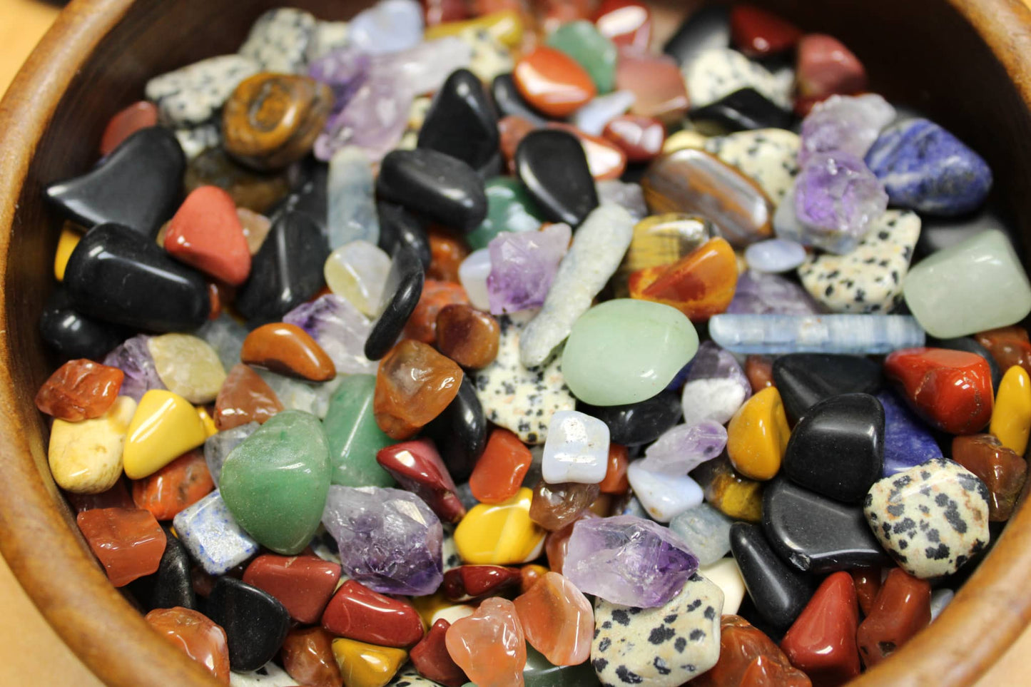 Assorted polished crystals and tumbled stones in wooden bowl for large gem mining mystery bag
