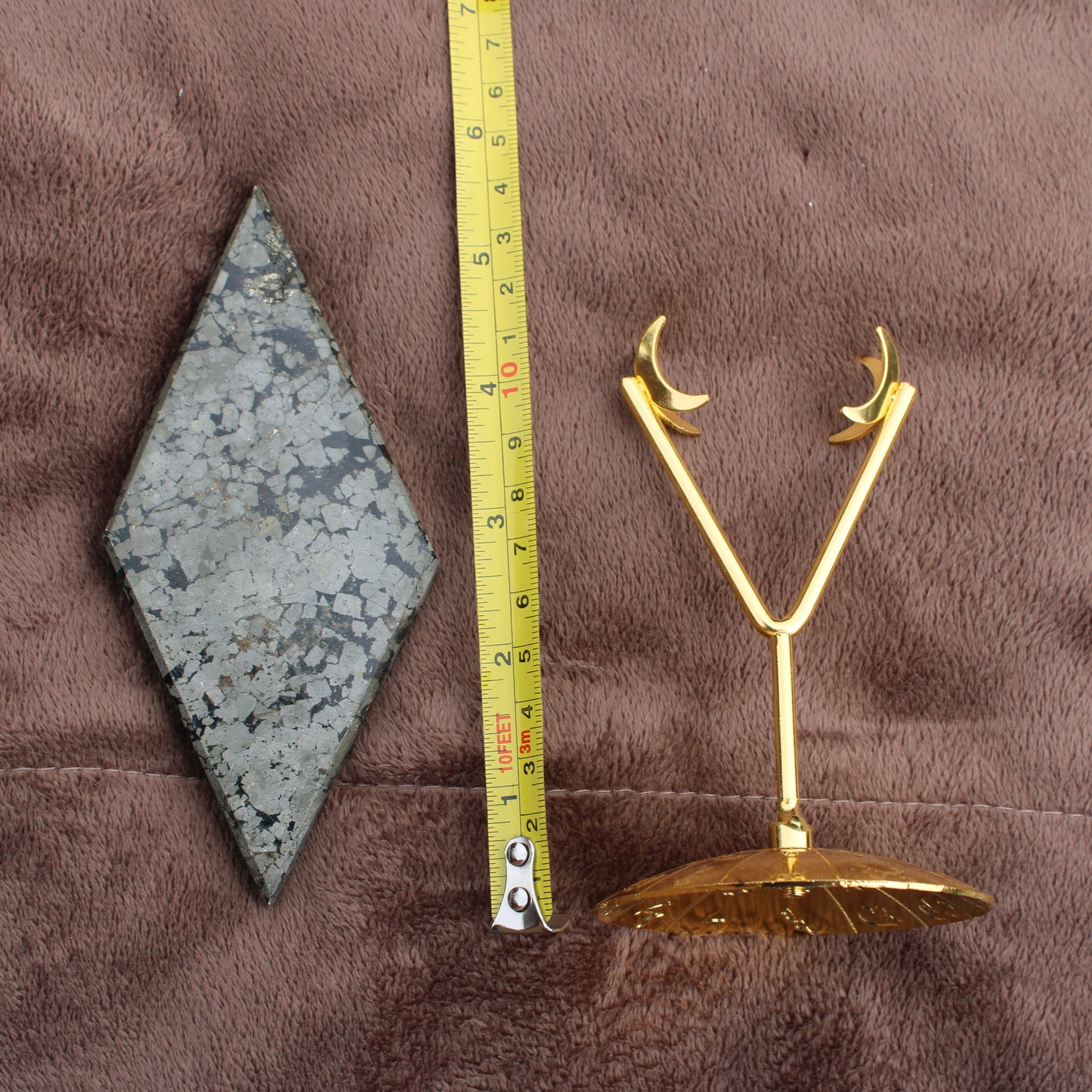 Pyrite Diamond crystal from Different Branches LLC displayed next to measuring tape and gold moon-shaped stand