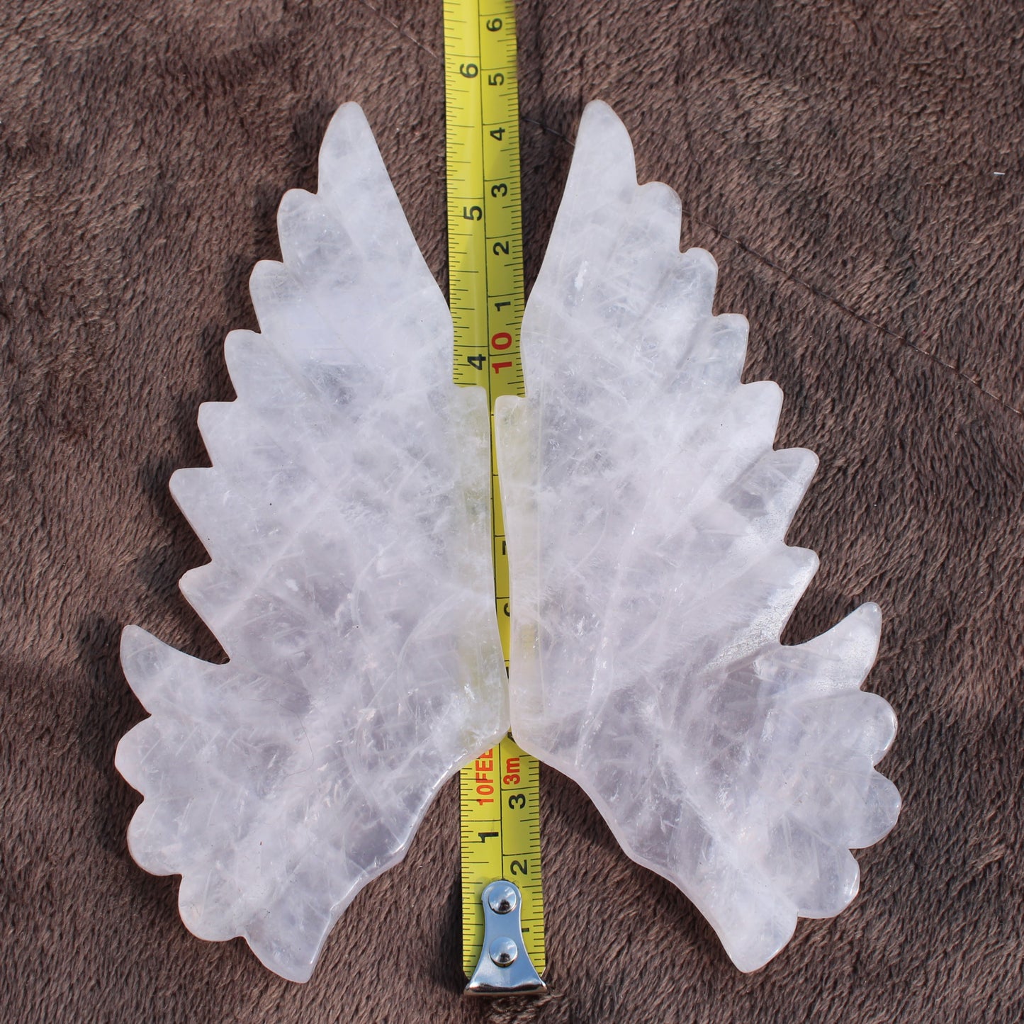 Different Branches LLC Quartz Owl Wings crystal carved paired wings with measuring tape on brown fabric