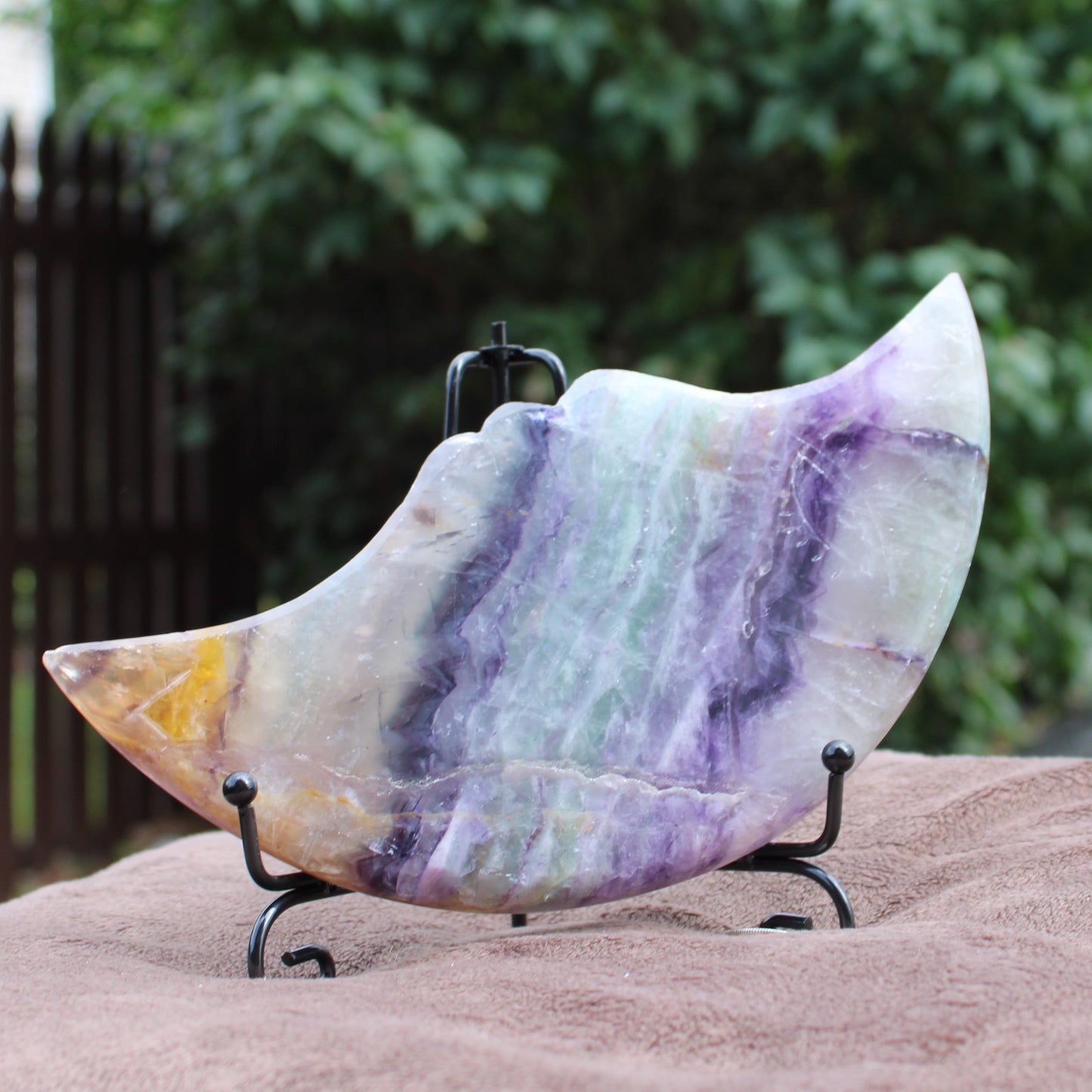 Rainbow Fluorite Cresent Moon Statement Crystal with purple and green hues on display stand