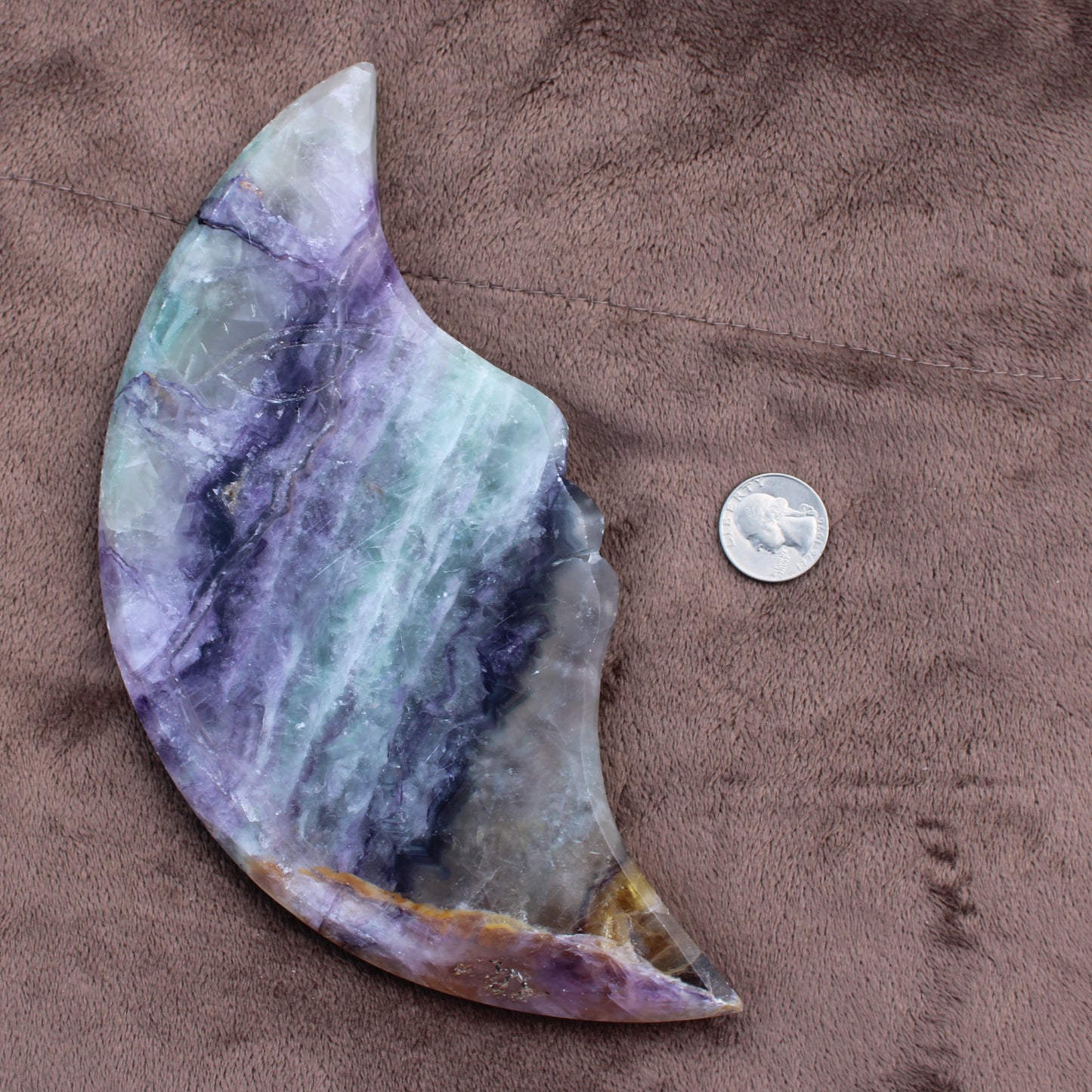 Rainbow Fluorite Cresent Moon Statement Crystal with purple and green hues next to a quarter for size reference