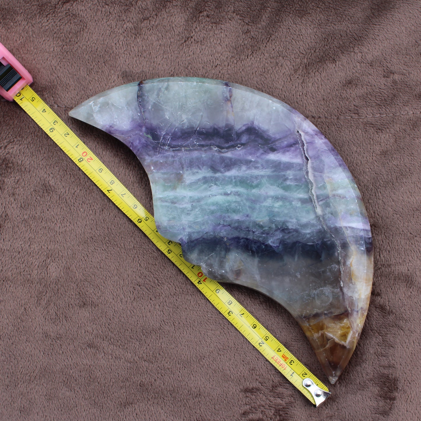 Rainbow Fluorite Cresent Moon Statement Crystal showcasing purple green and brown hues with measuring tape