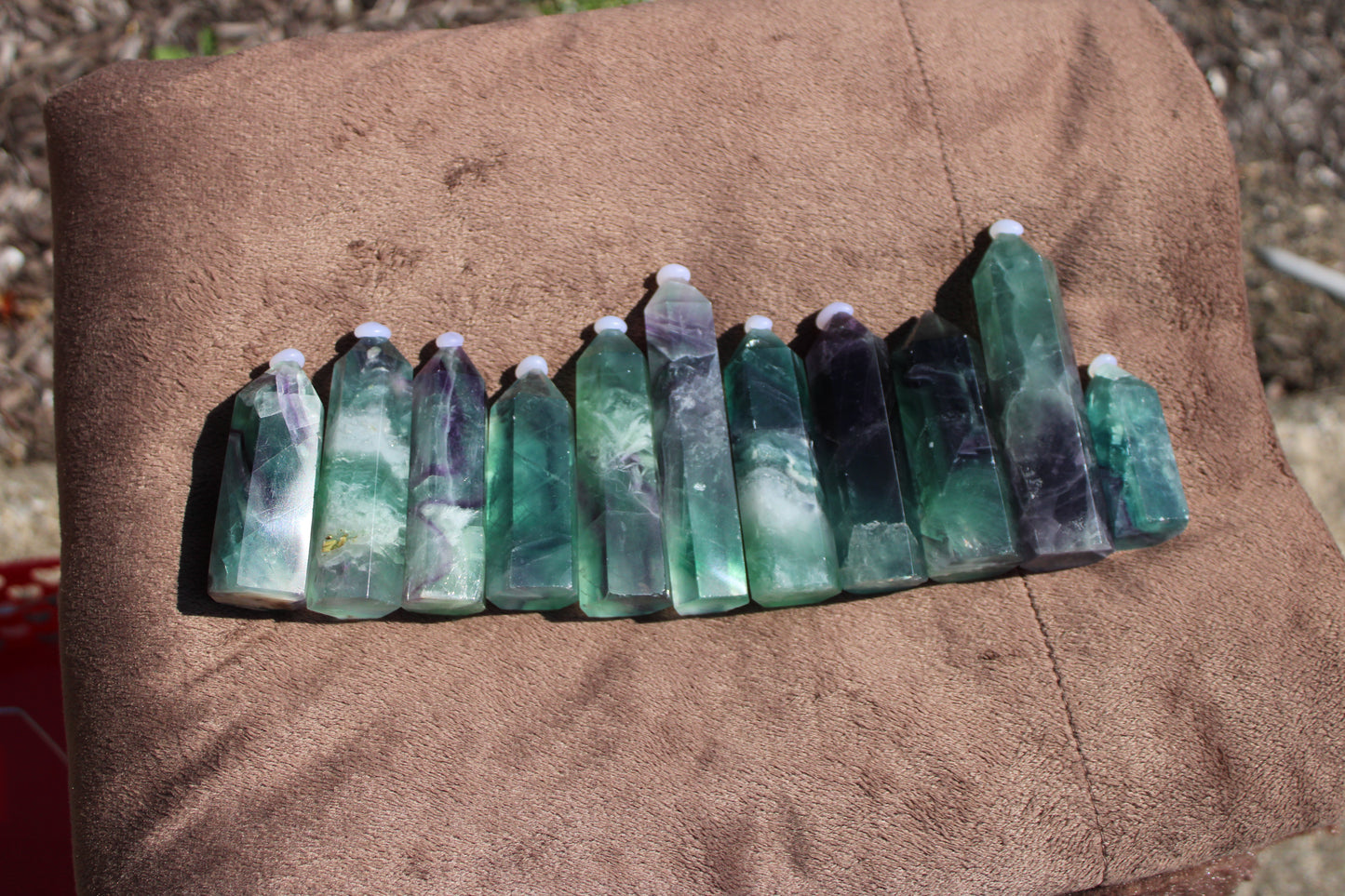 Collection of Rainbow Fluorite tower crystals in various shades of green and purple, arranged neatly
