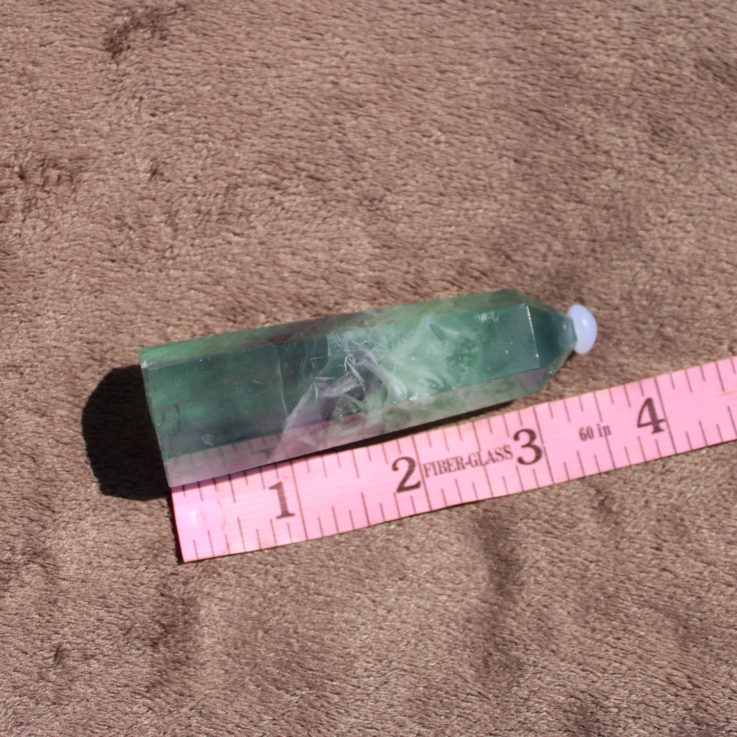 Rainbow Fluorite tower showcasing vibrant colors and unique patterns on a soft surface