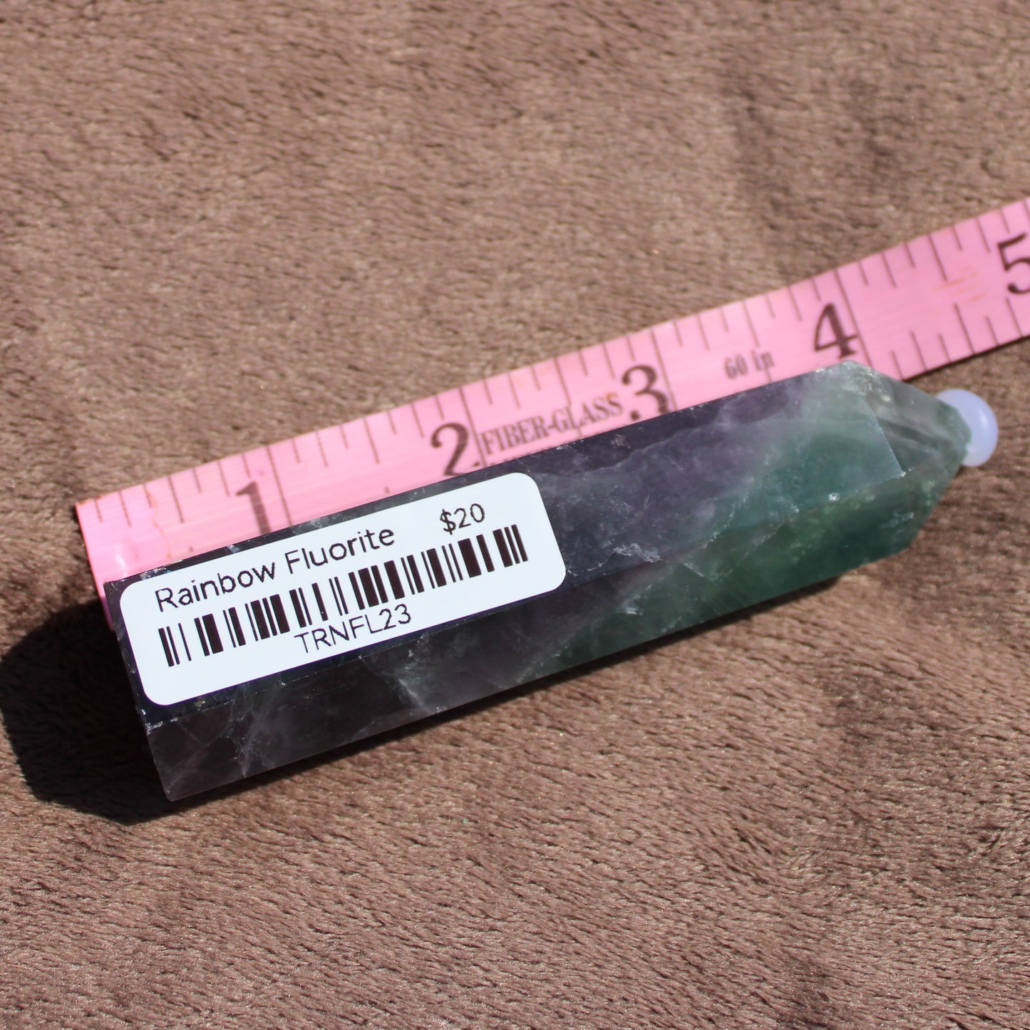 Rainbow Fluorite tower displayed with a ruler for size reference, showcasing its vibrant colors