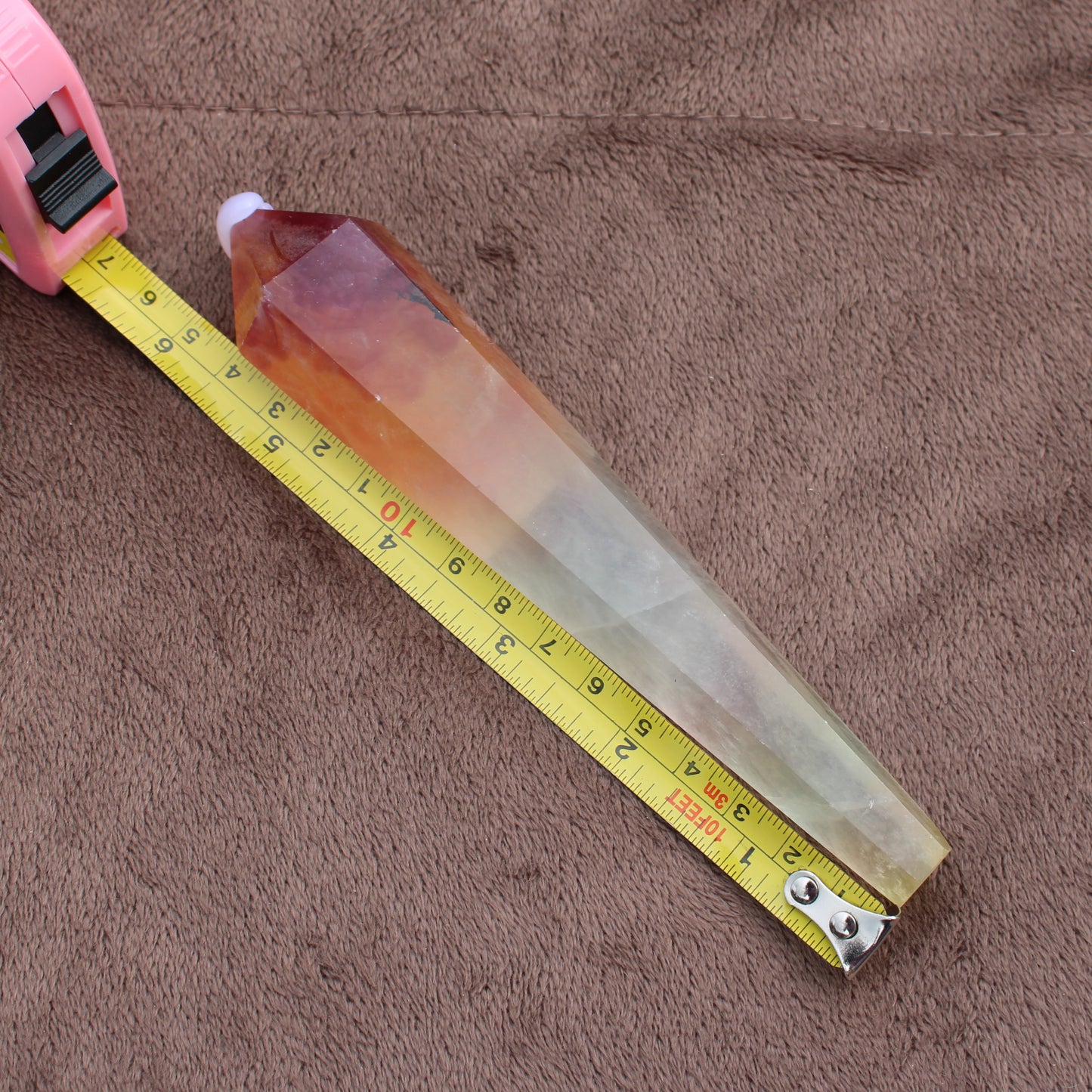 Rainbow Fluorite Wand measuring approximately 6 inches with a pointed crystal tip on brown fabric