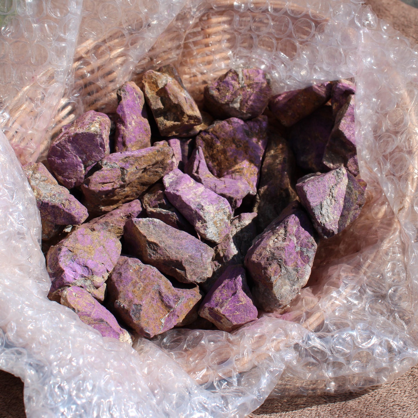 Raw Phosphosiderite crystal pieces in a woven basket with protective bubble wrap
