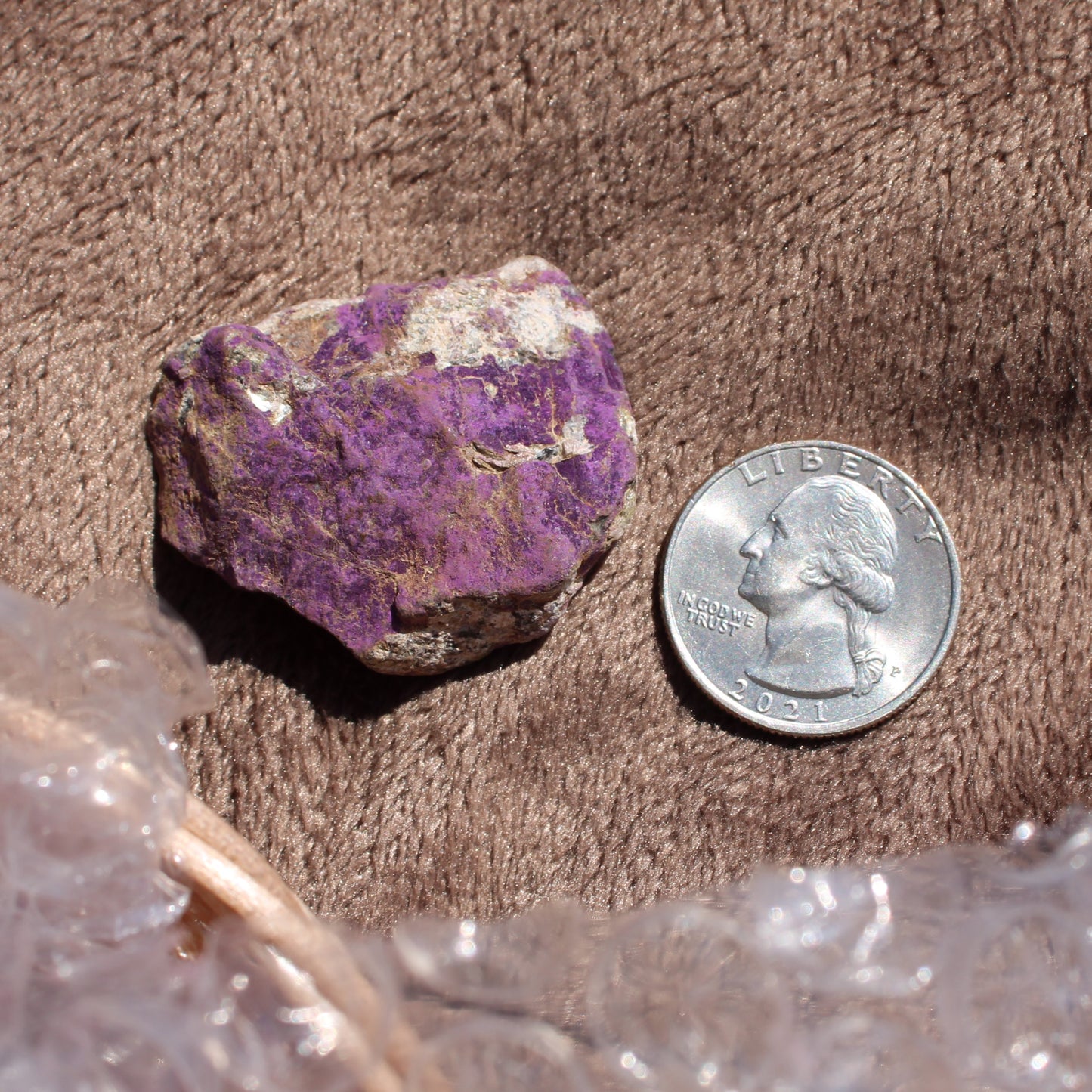 Raw Phosphosiderite crystal in purple next to a quarter for size reference