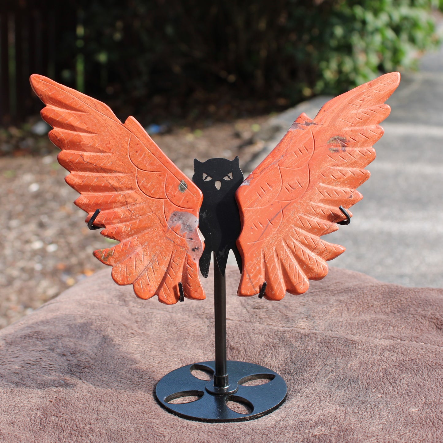 Red Jasper Owl Wings crystal display by Different Branches LLC on metal stand outdoors
