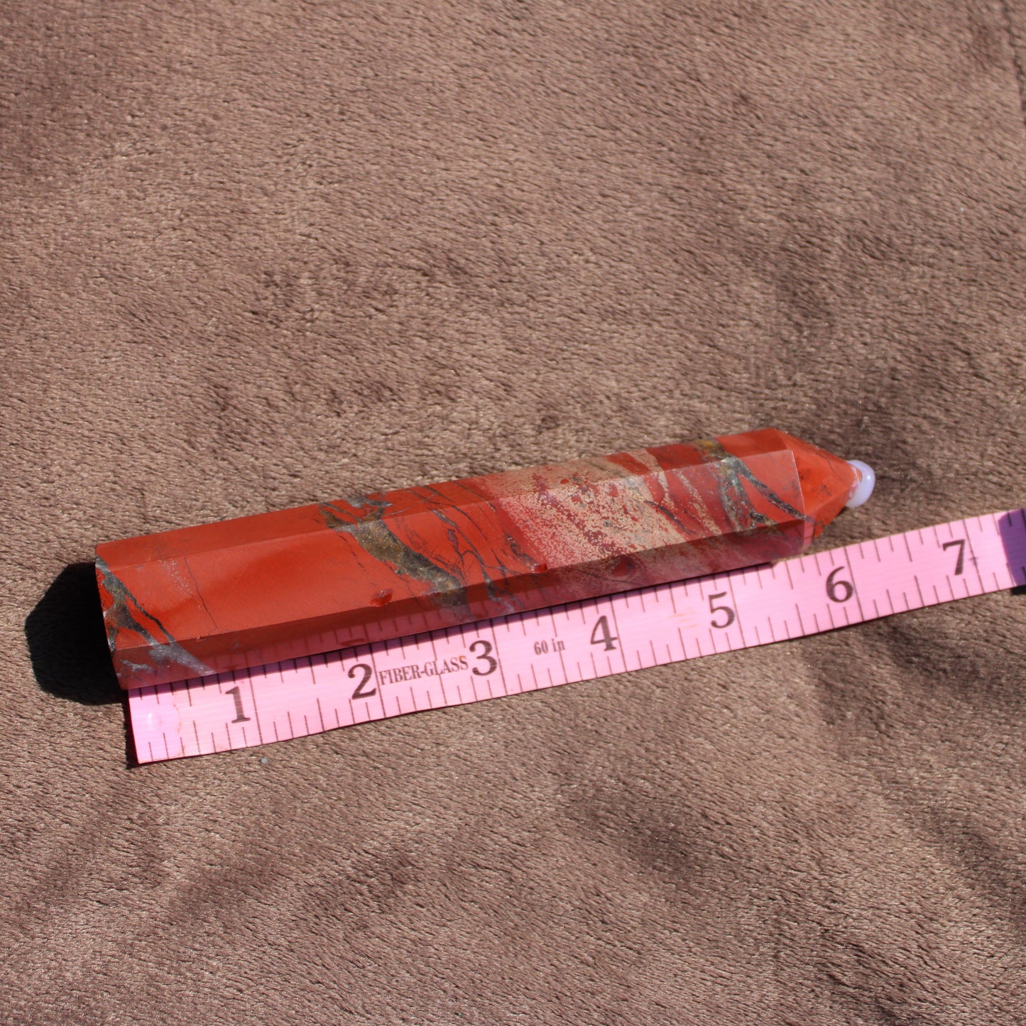 Red jasper tower crystal with unique patterns and smooth finish on a soft background