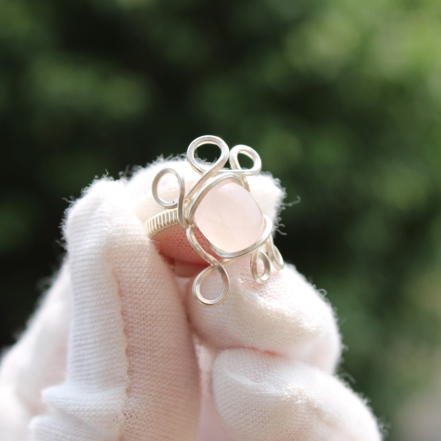 Handcrafted silver setting holding a rose quartz ring size 3 with unique swirl design