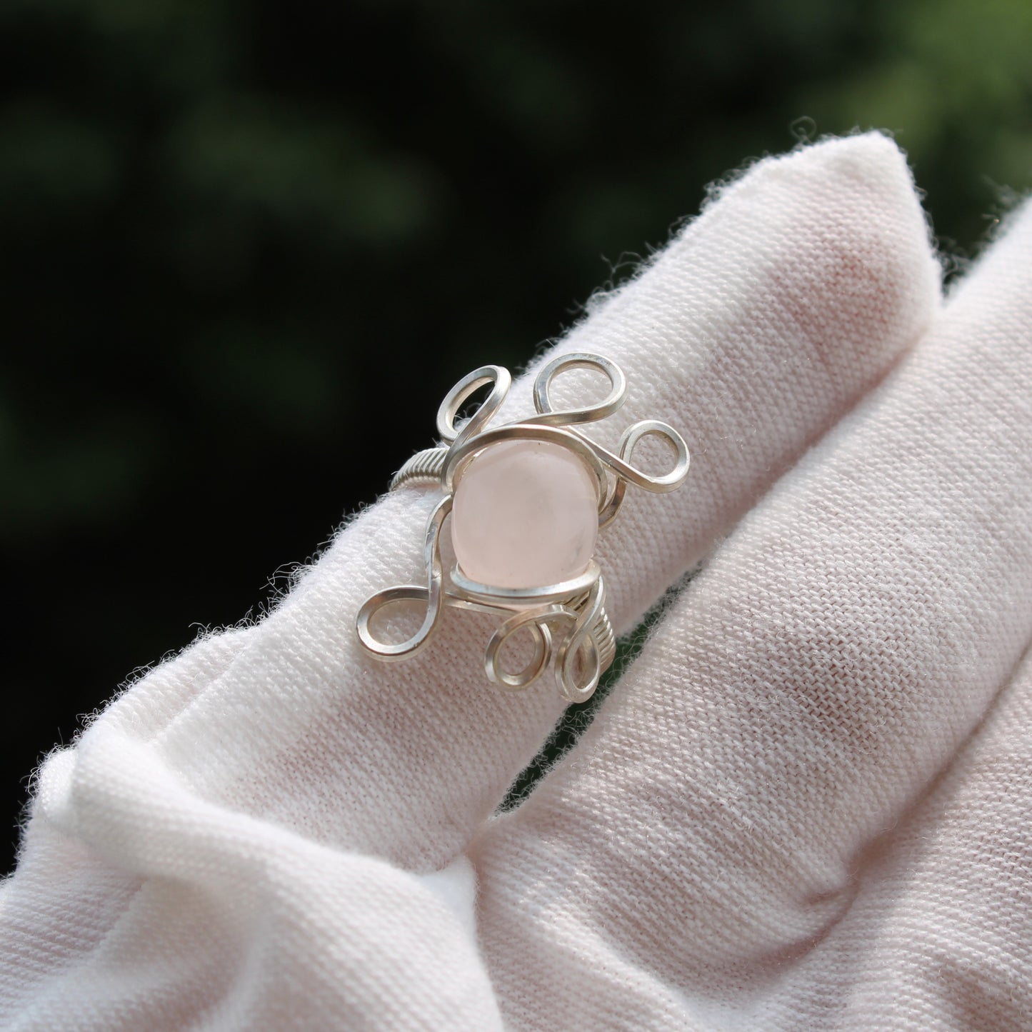Handcrafted rose quartz ring size 3 with silver wire design, shown on a hand with a soft background