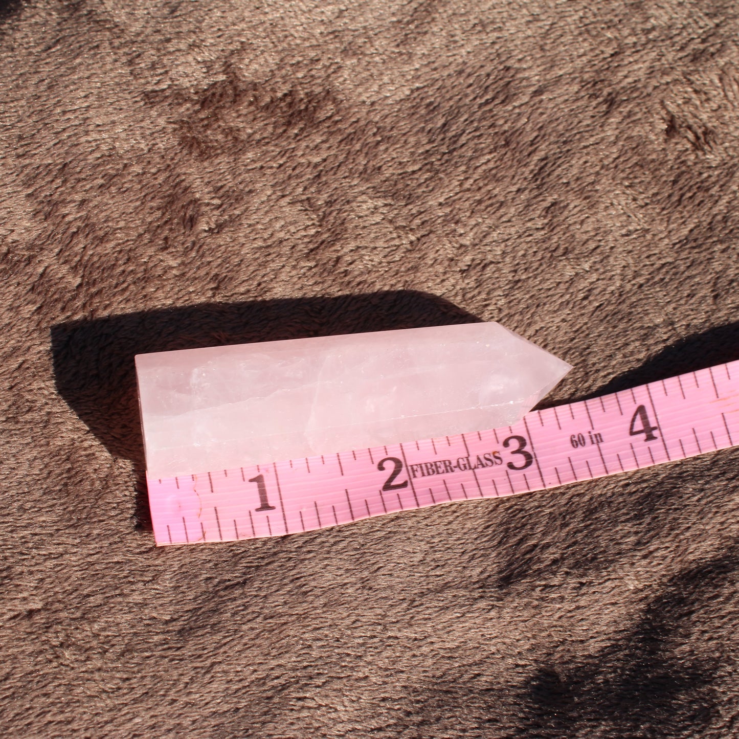 Rose Quartz tower with smooth edges, measuring approximately 3 inches in height on a textured surface