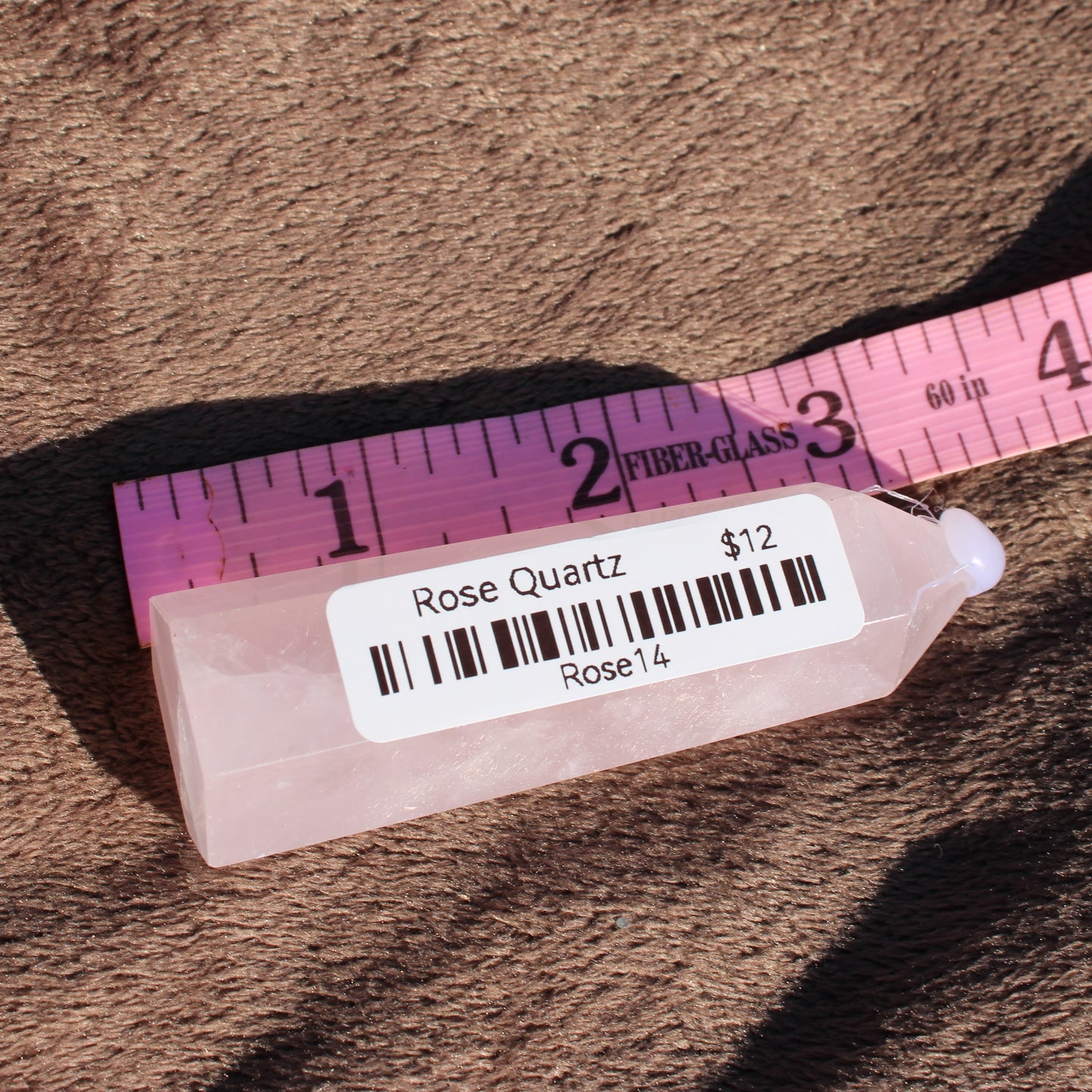 Rose Quartz tower displayed with a ruler for scale, showcasing its natural beauty and soft pink color