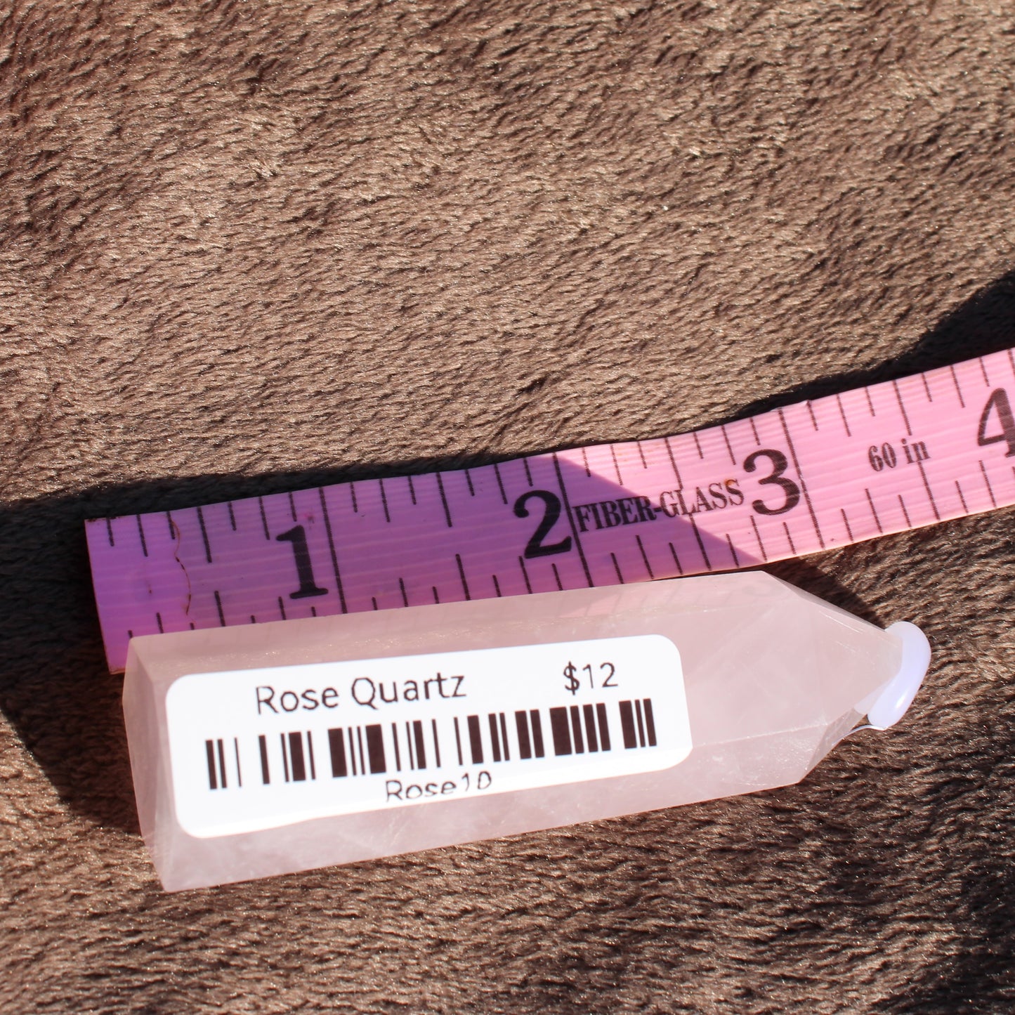 Rose Quartz tower displayed with a ruler to show size and detail for crystal enthusiasts
