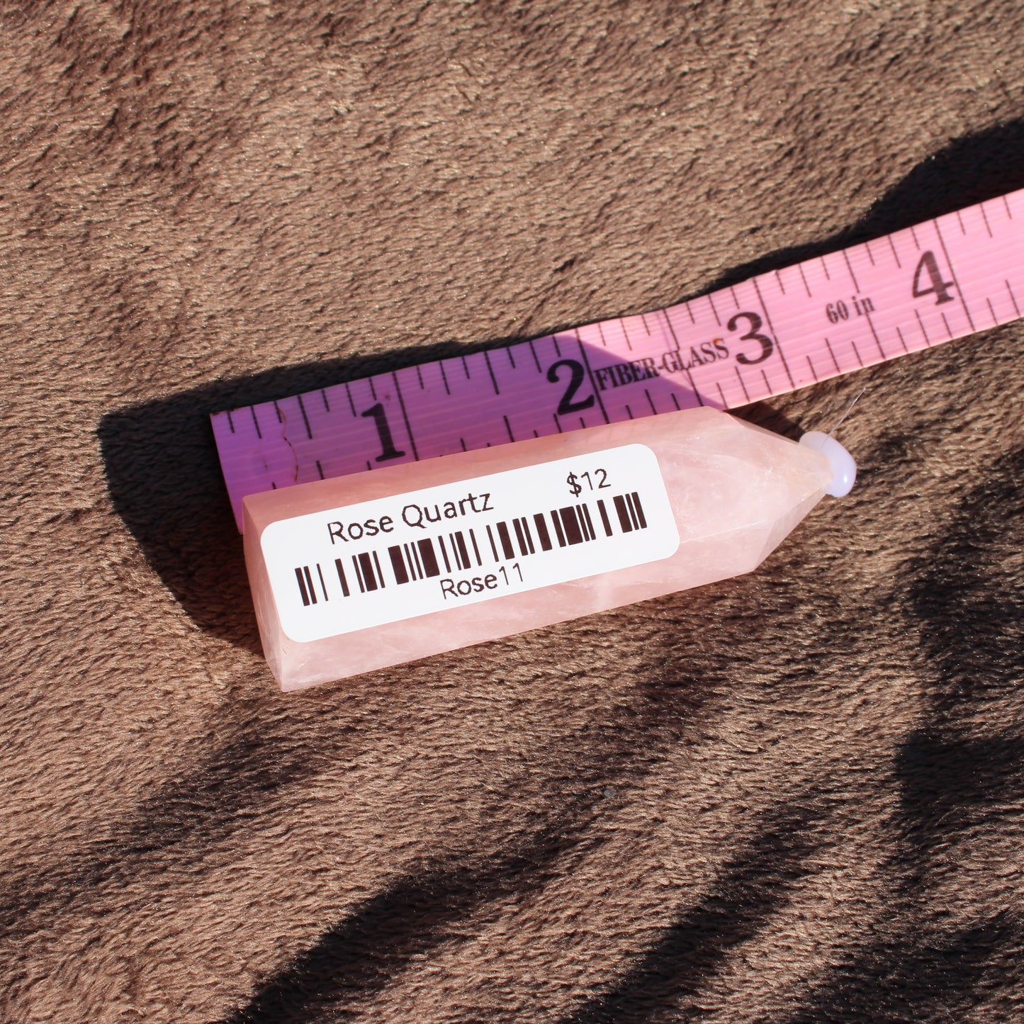 Authentic Rose Quartz tower displayed on a soft surface with a price tag showing twelve dollars