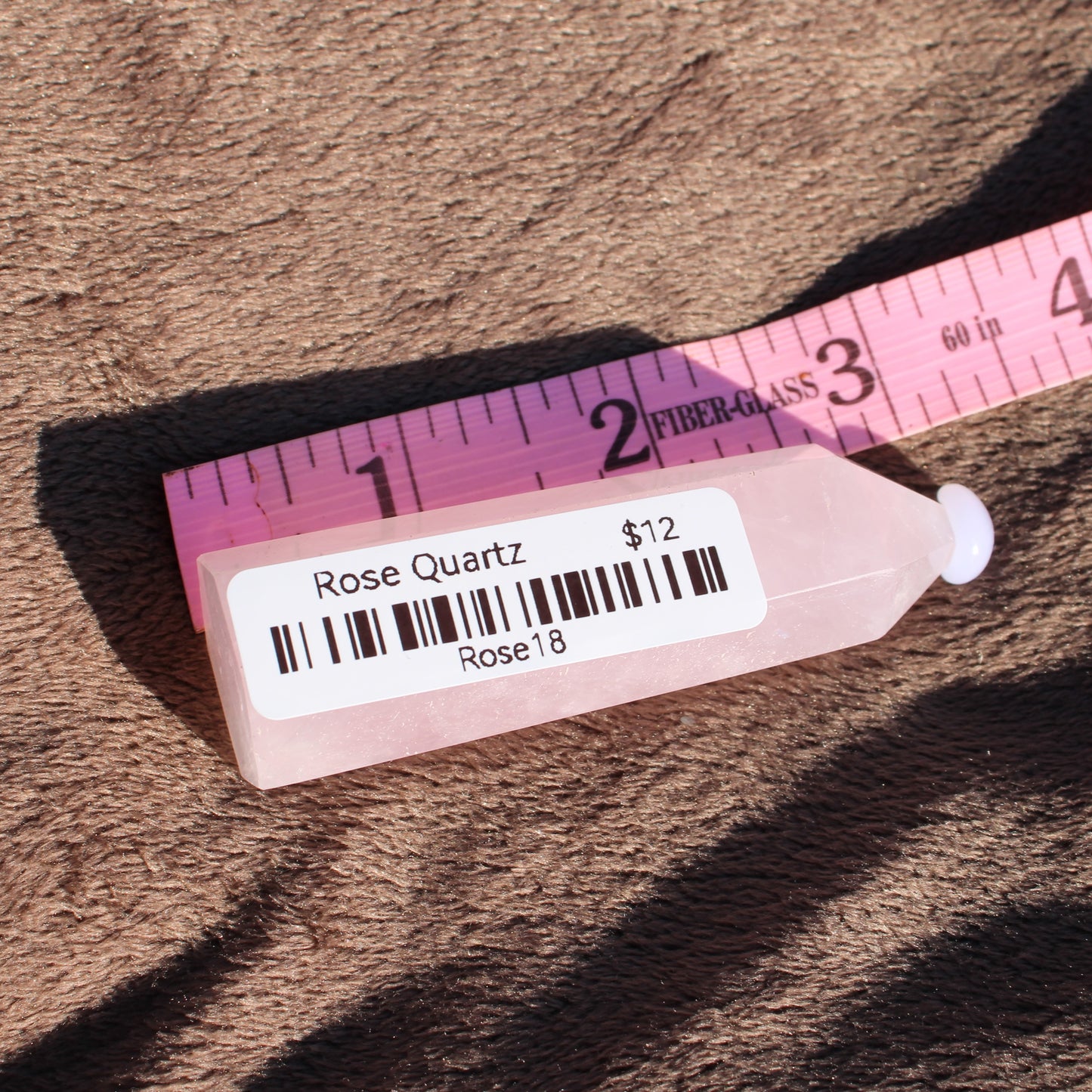 Rose Quartz tower displayed next to a ruler for size reference with a soft background