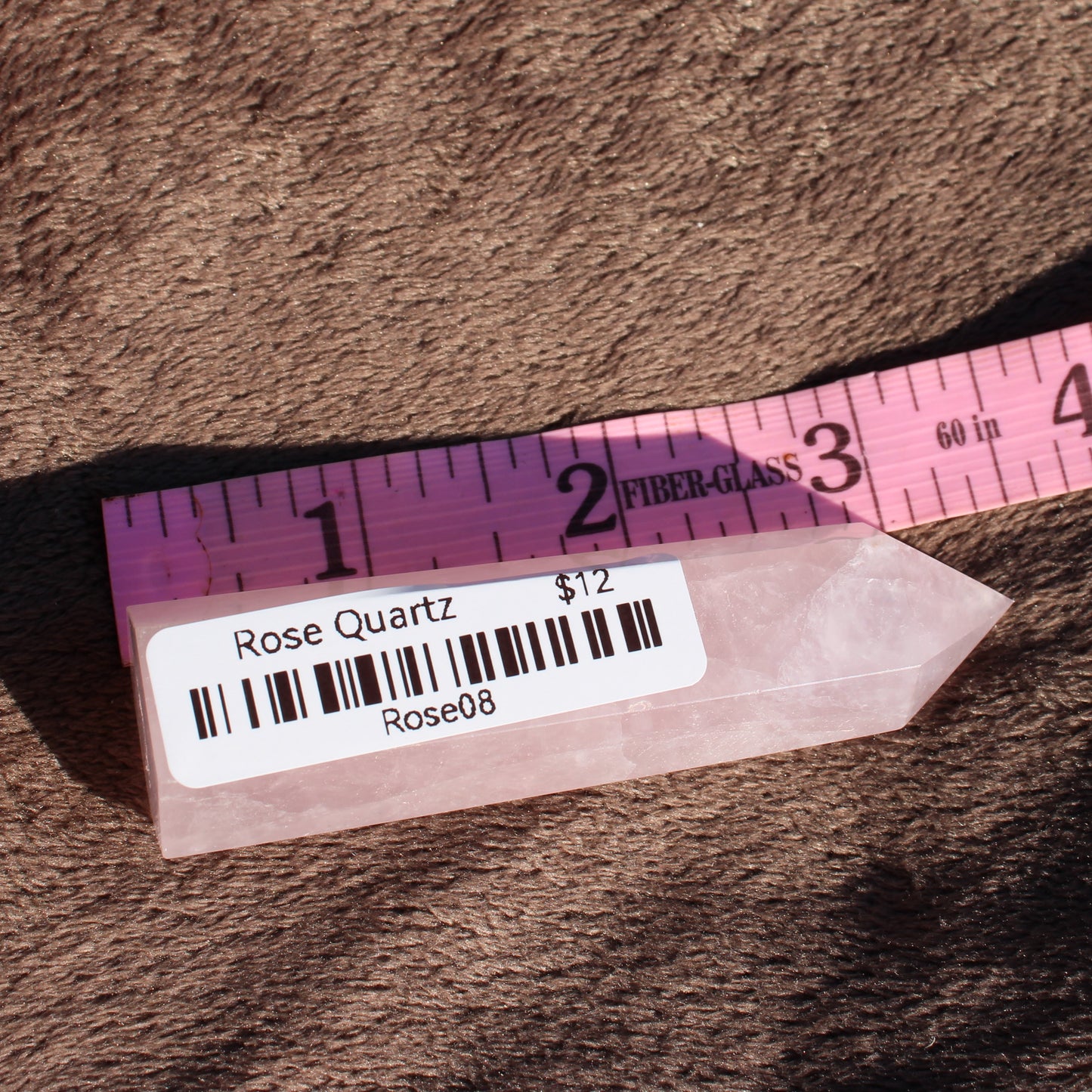 Polished Rose Quartz tower displayed alongside a measuring tape for size reference
