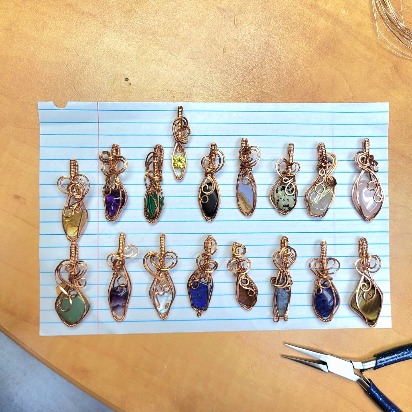Handcrafted Jewelry Pendants with Various Stones including Rose Quartz on Blue Line Paper