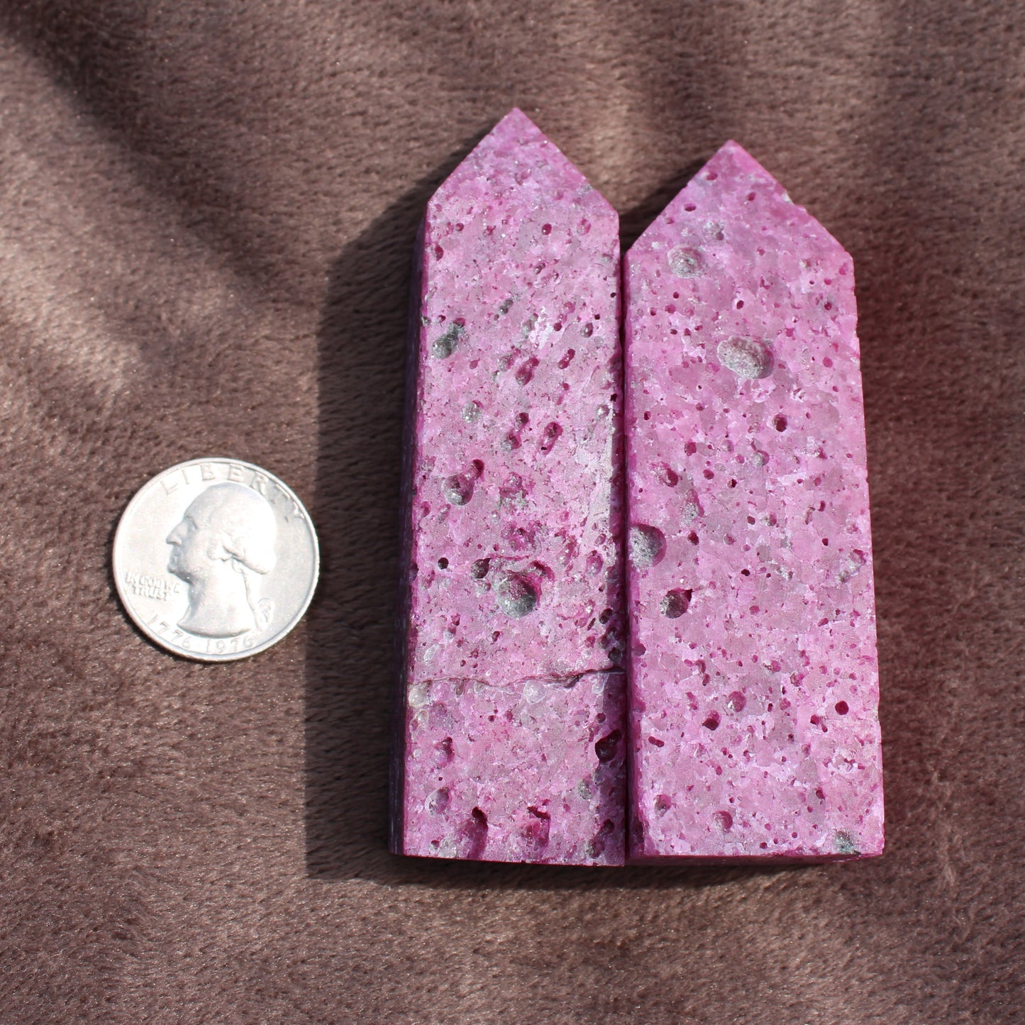 Two Ruby Tower crystals in pink with porous texture next to a US quarter for size comparison