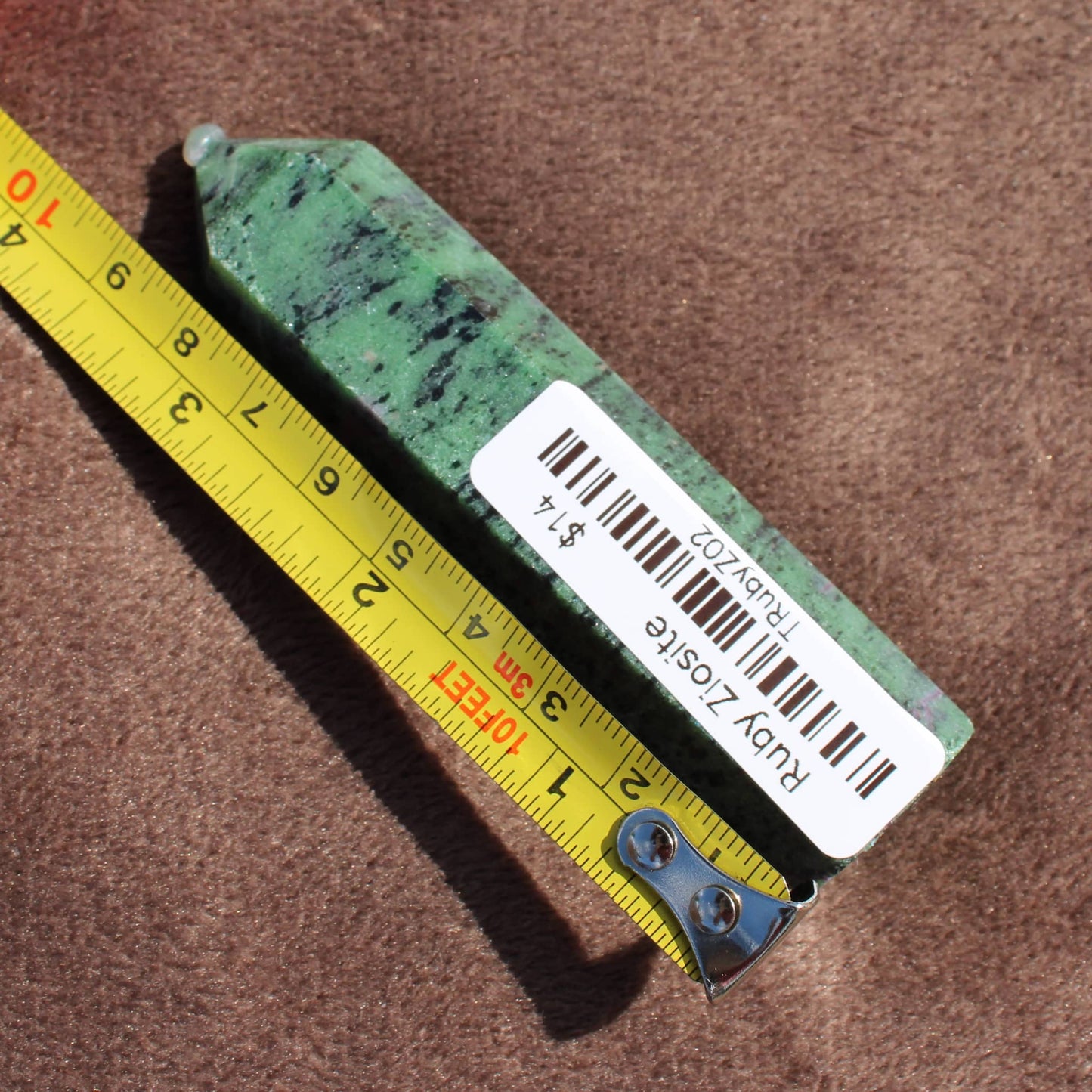 Green and black Ruby Zoisite Tower crystal from Different Branches LLC next to a measuring tape